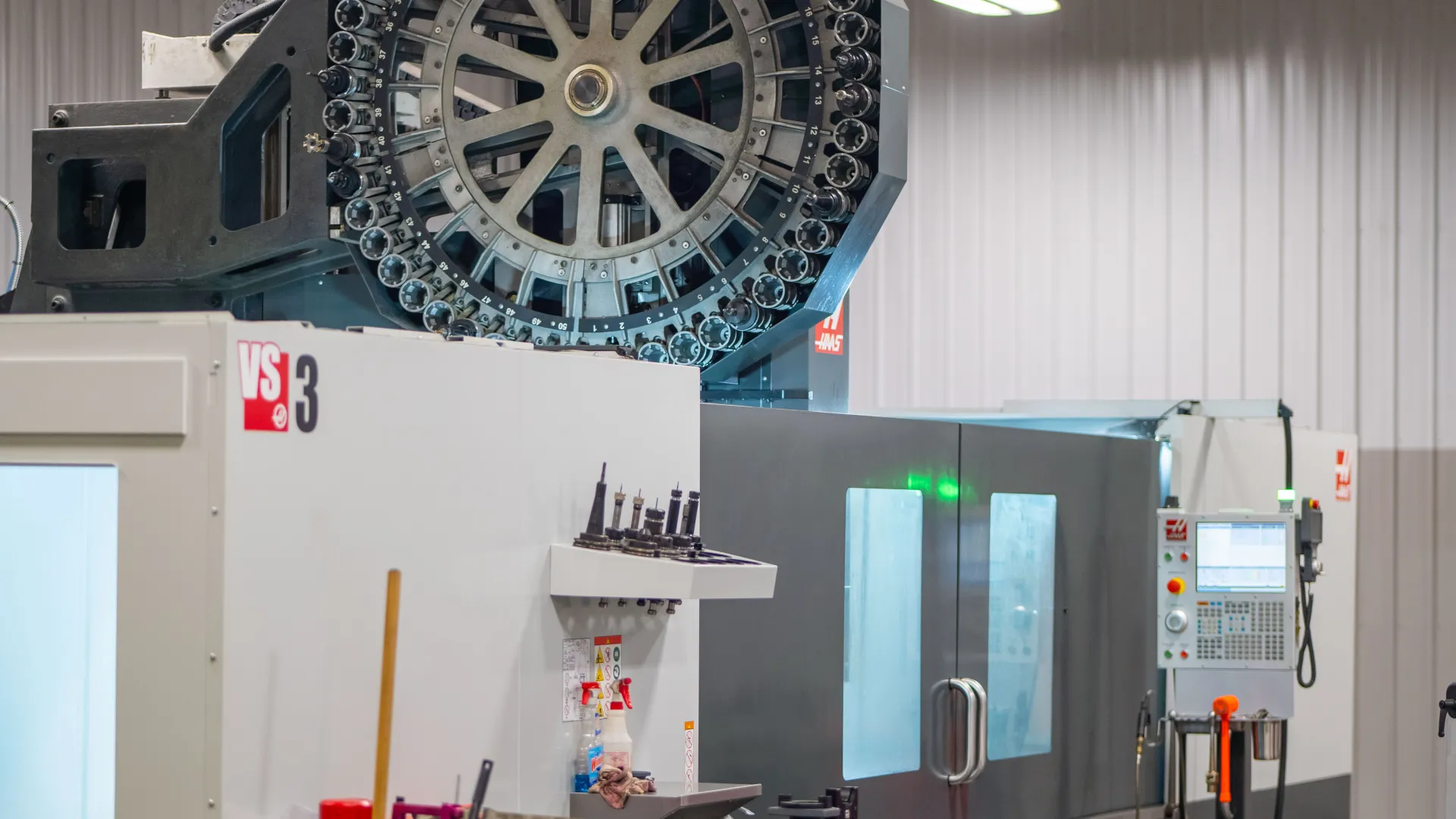 Industrial CNC machining center with tool carousel and control panel in a clean workshop environment