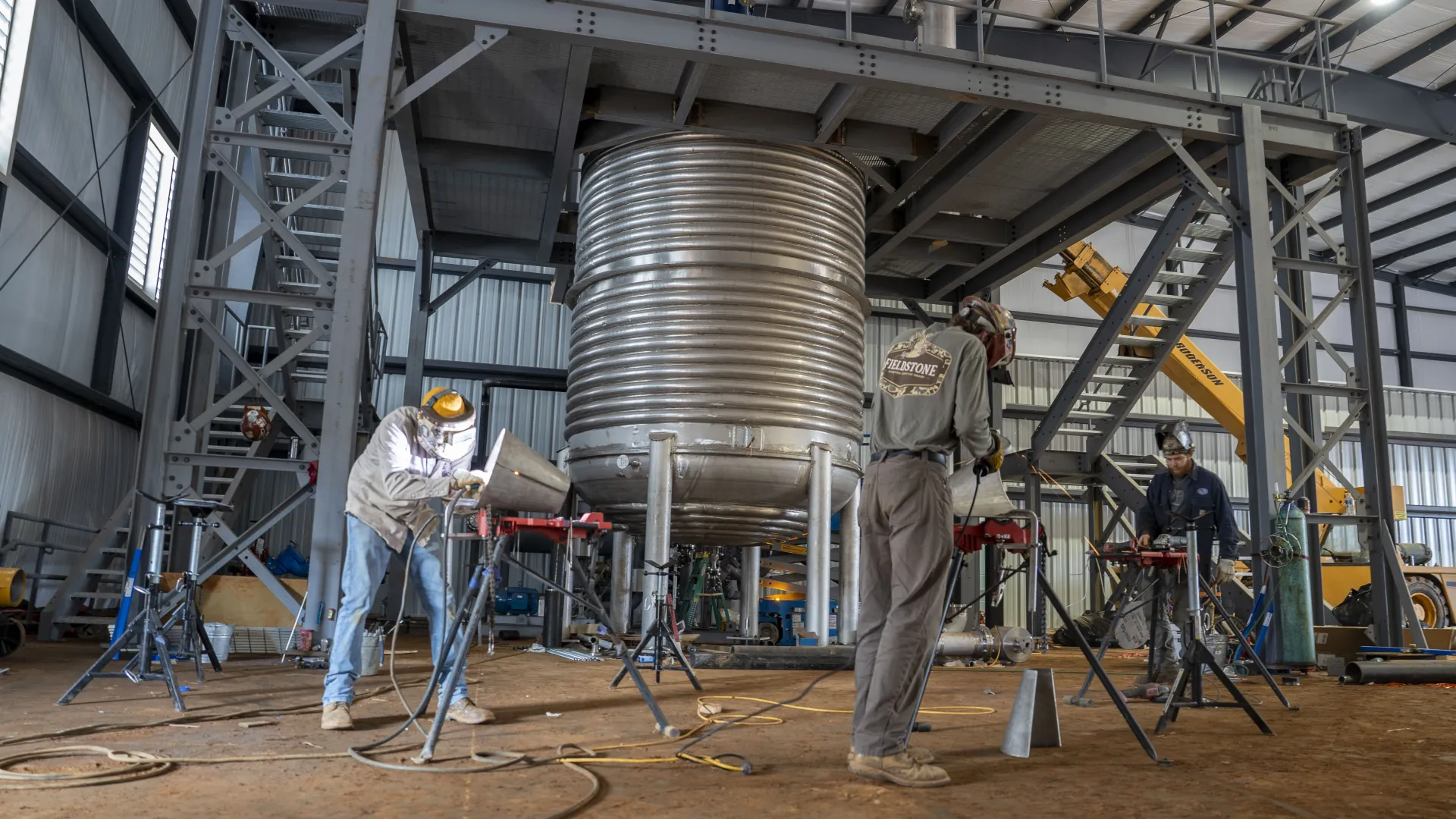 Silhouette of scaffolding and building structure against a gradient sunset sky with sun flare.