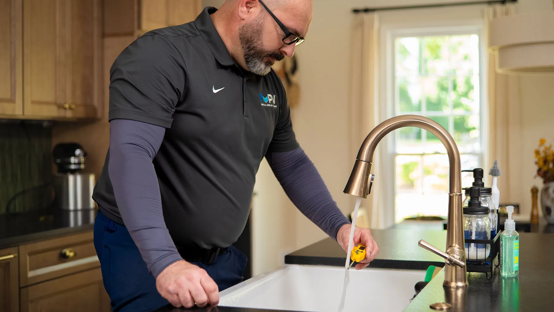 Professional plumber testing water flow from kitchen faucet in a modern home with yellow gauge