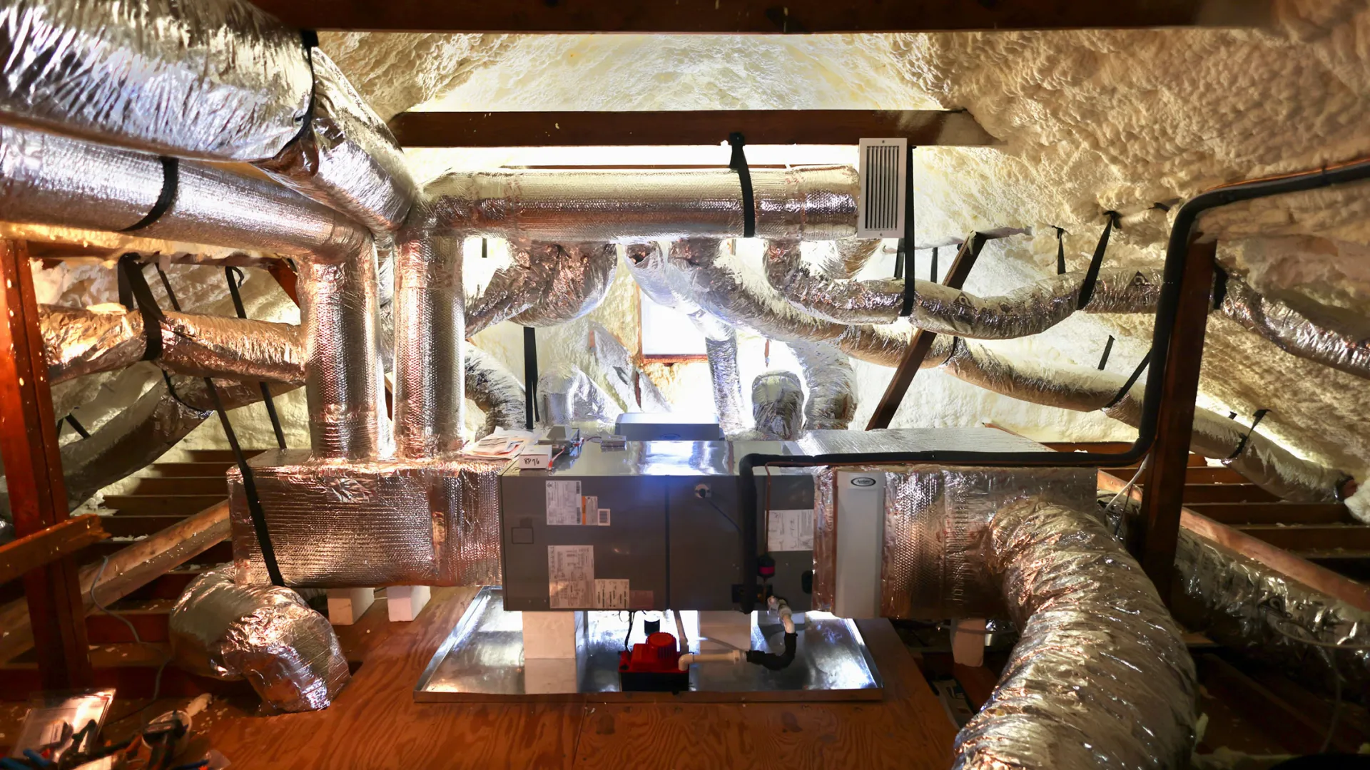Insulated HVAC ductwork and furnace system installed in an attic with spray foam insulation.