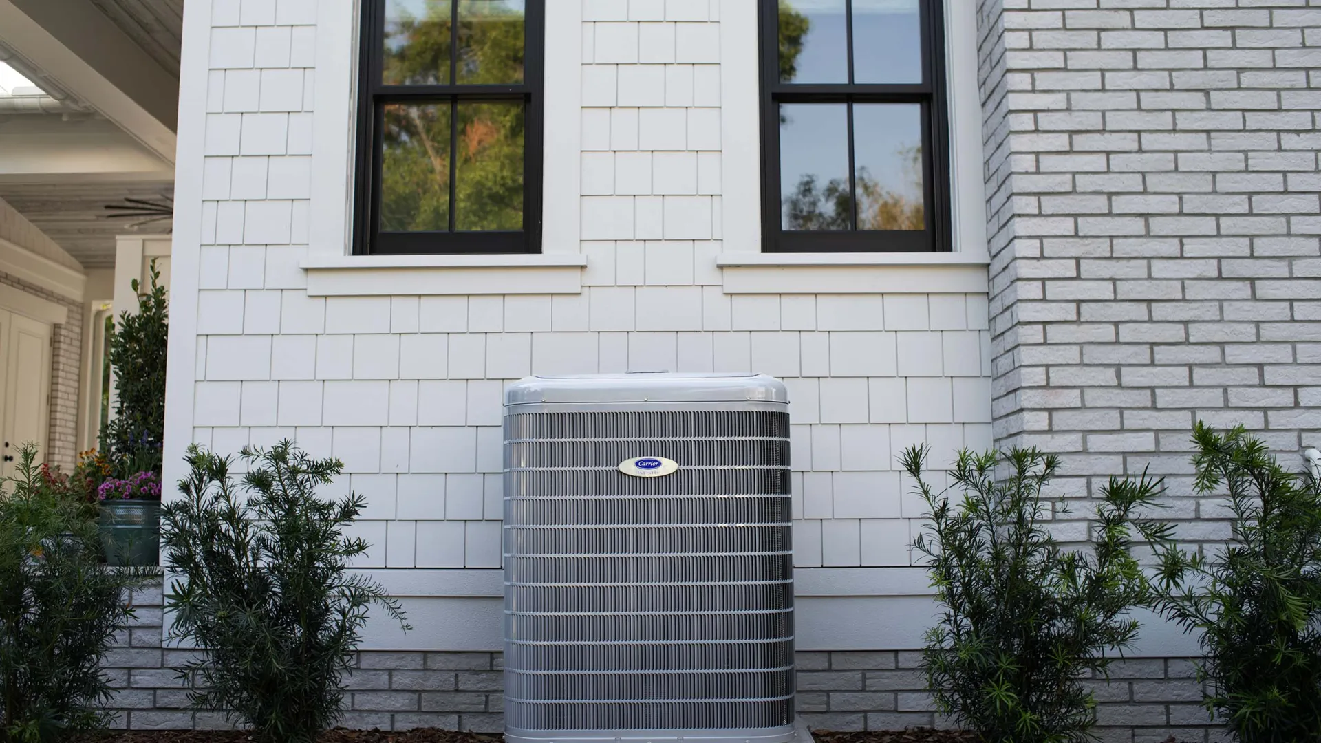 Energy-efficient air conditioning unit placed beside a modern home with a garden.