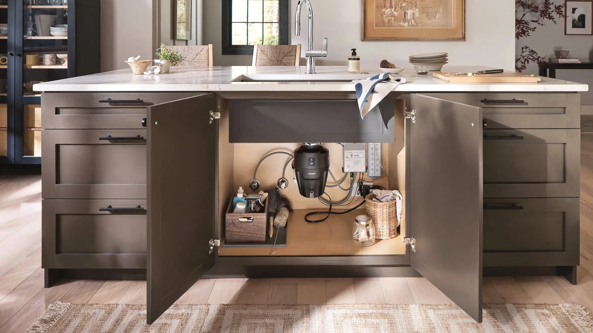 Open kitchen cabinet showing installed garbage disposal unit and organized cleaning supplies underneath sink.