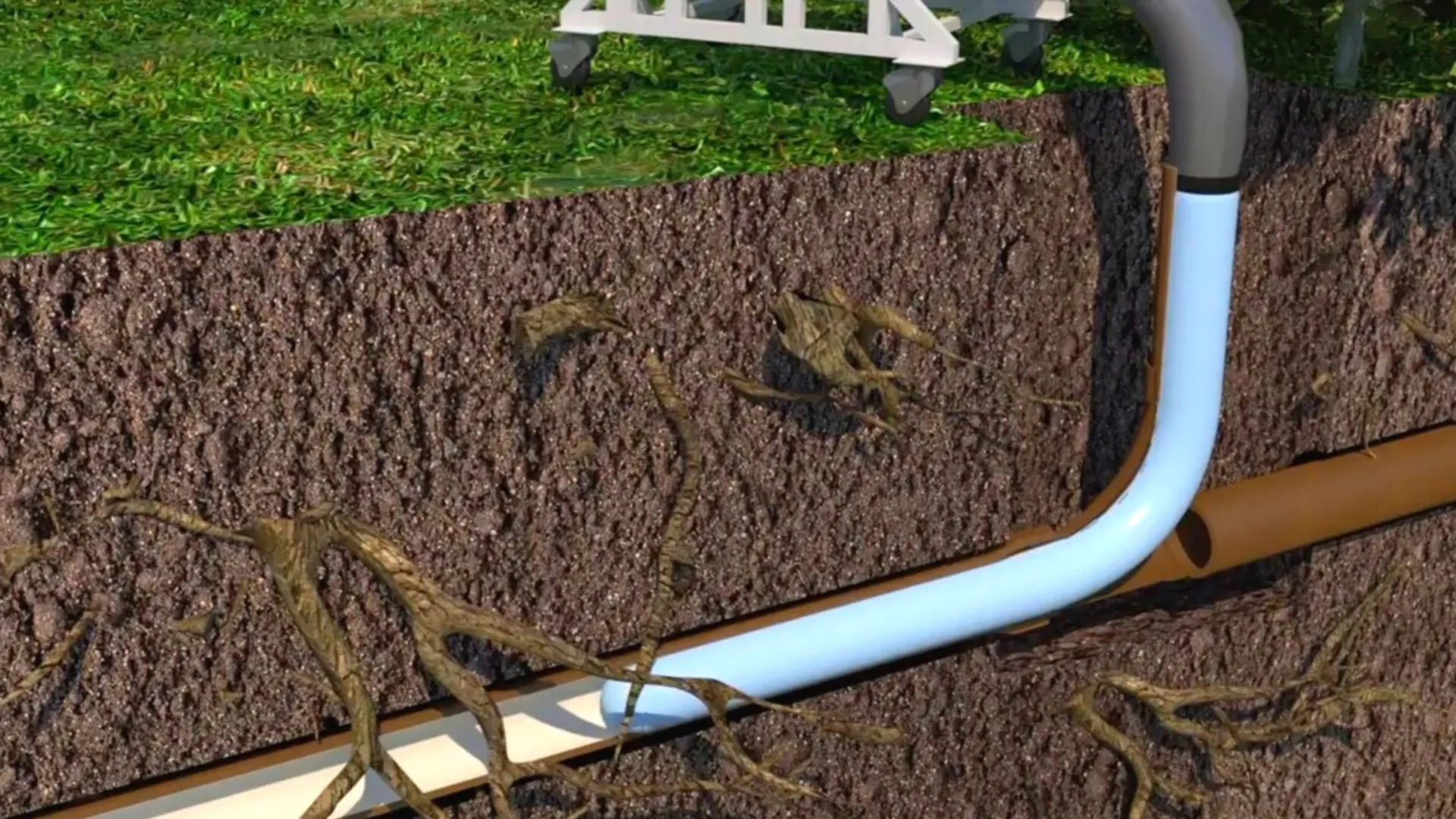 Cross-section of soil showing underground drainage pipes and roots beneath green grass surface.