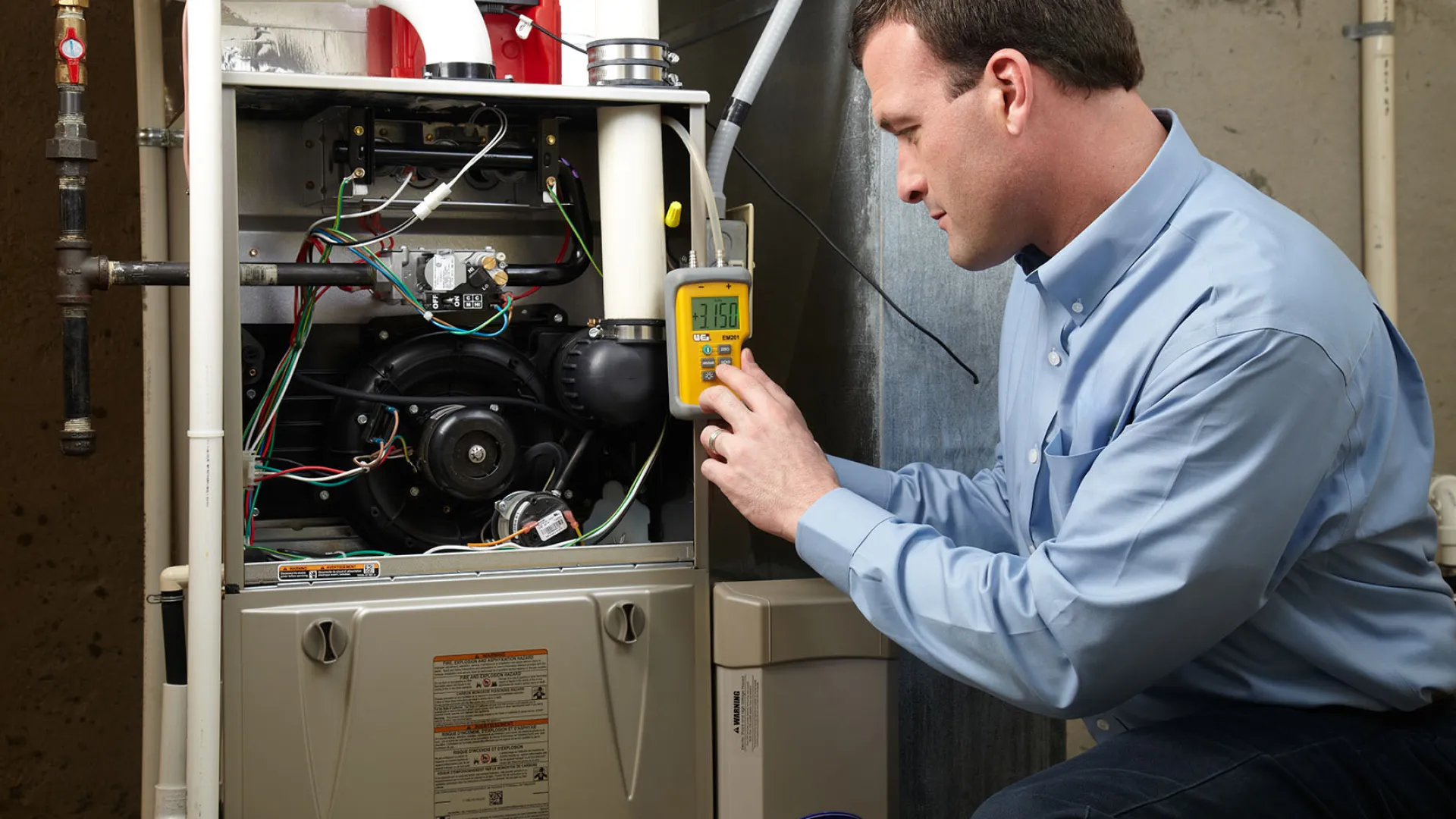 Technician inspecting a furnace with diagnostic tools in a residential setting.