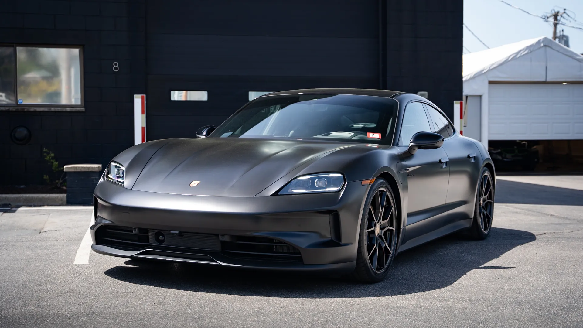 Matte black Porsche sports car parked outdoors with modern design and sleek body lines in daylight.