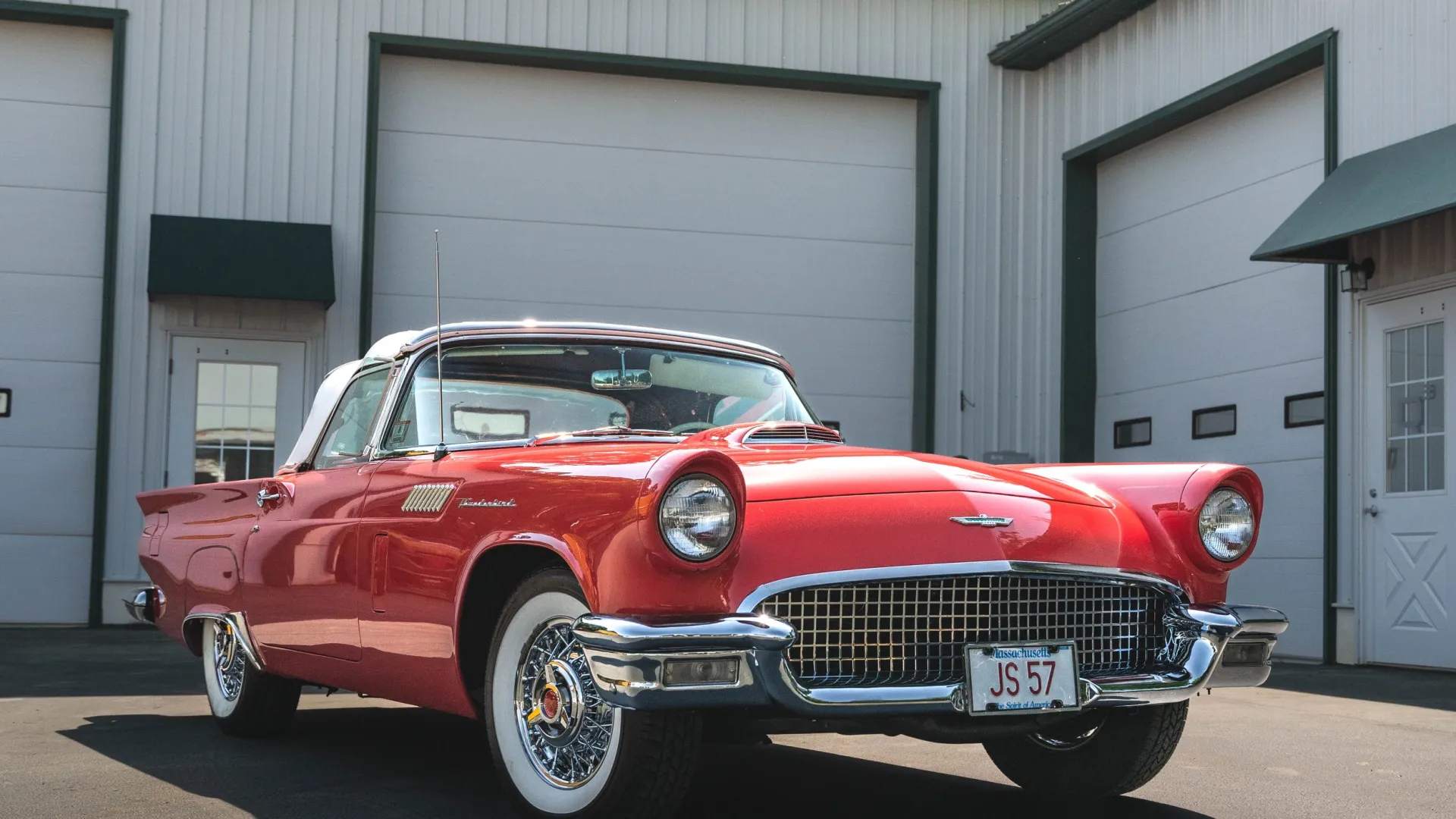 a red car parked in front of a garage