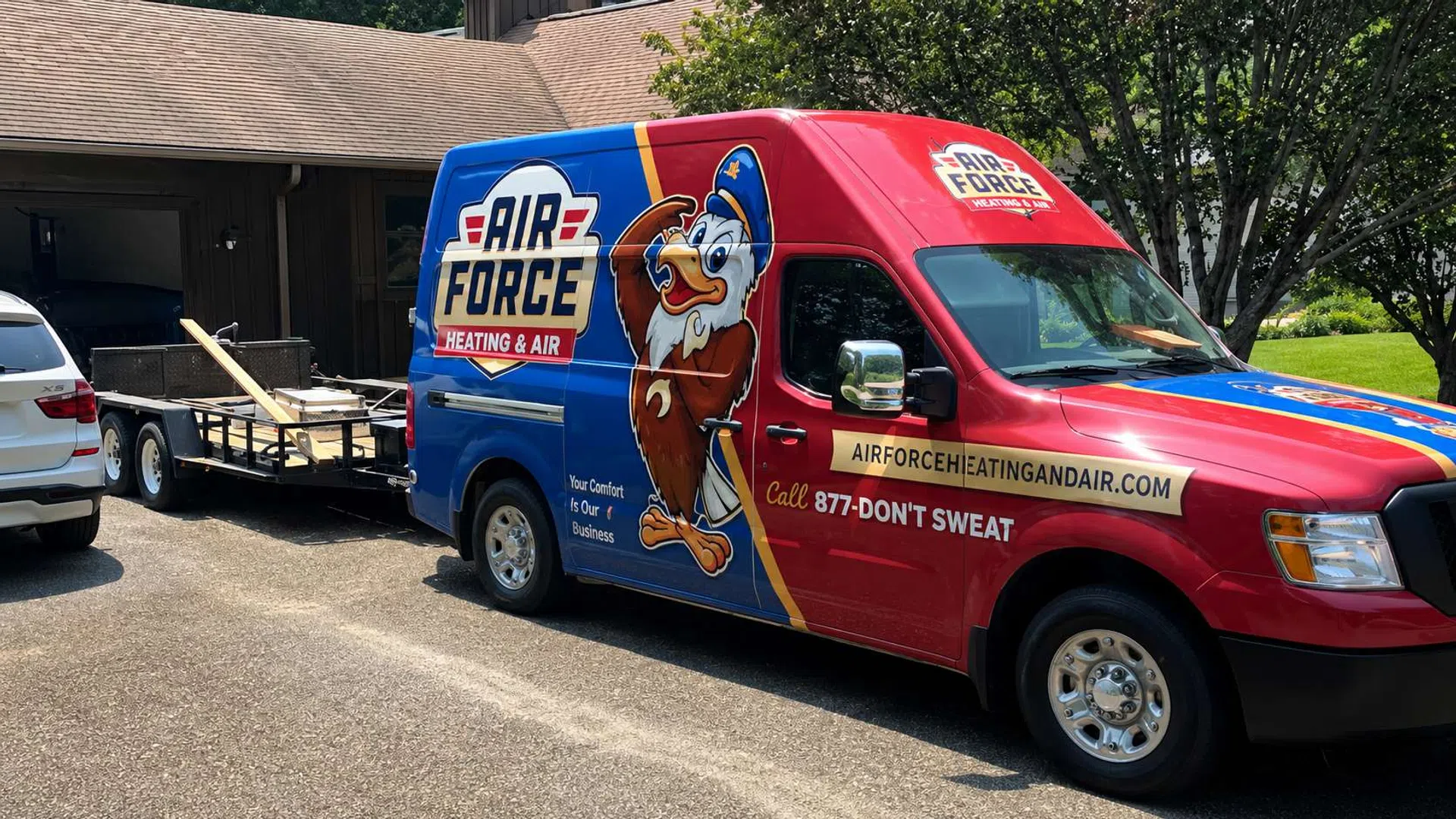 Air Force Heating & Air service van with colorful eagle logo parked outside a house, towing a trailer with equipment.