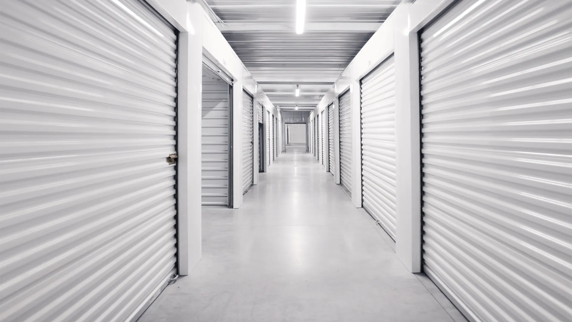 Long corridor of white storage units with closed roll-up doors and concrete floor in a clean facility