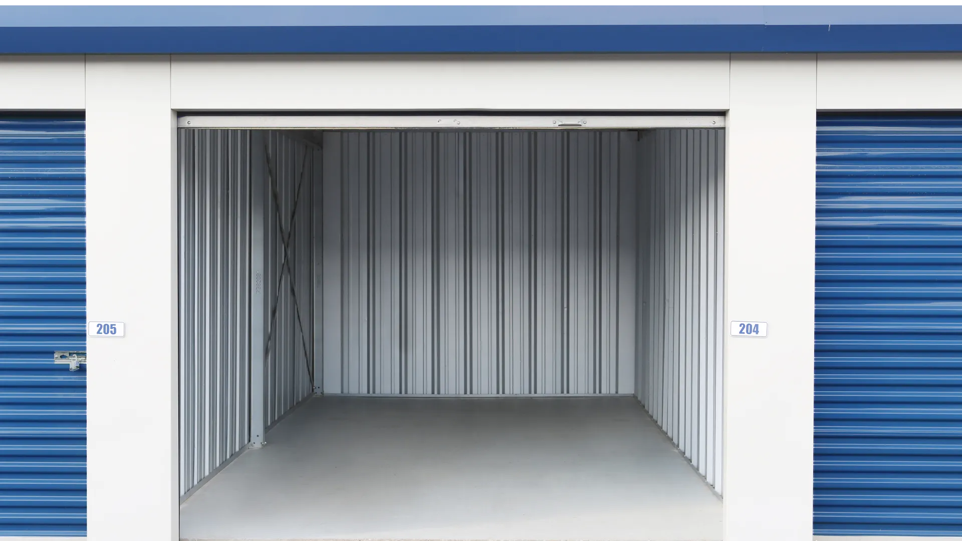 Empty storage unit with open blue roll-up door and metal walls in a self-storage facility.