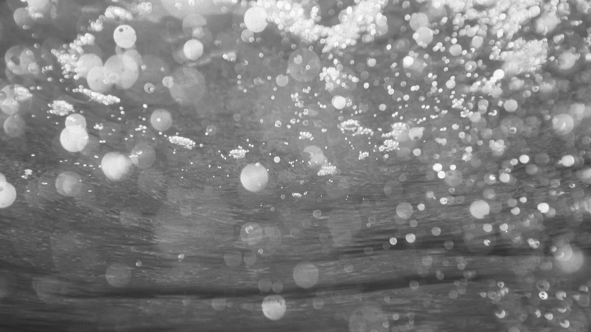 Black and white underwater bubbles rising with light reflections and abstract water patterns