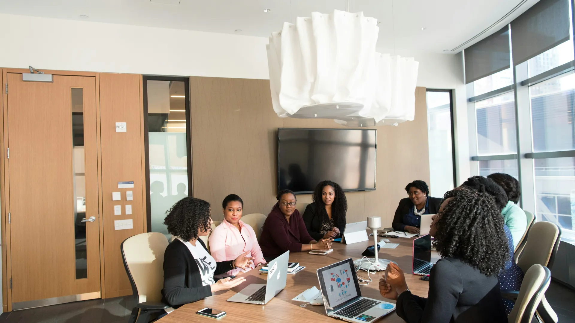 a group of people sitting around a table with laptops