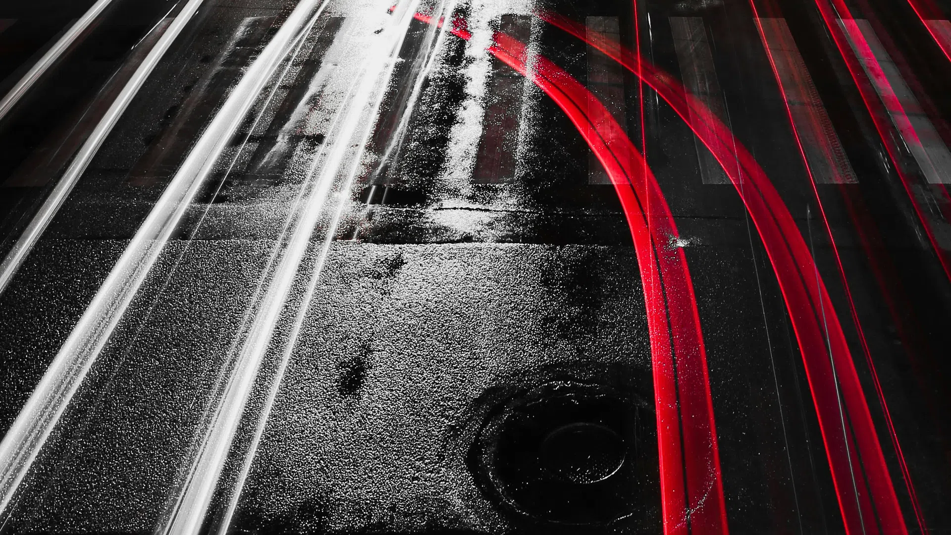 Long exposure of red and white light trails on wet city street at night with trees and cars nearby