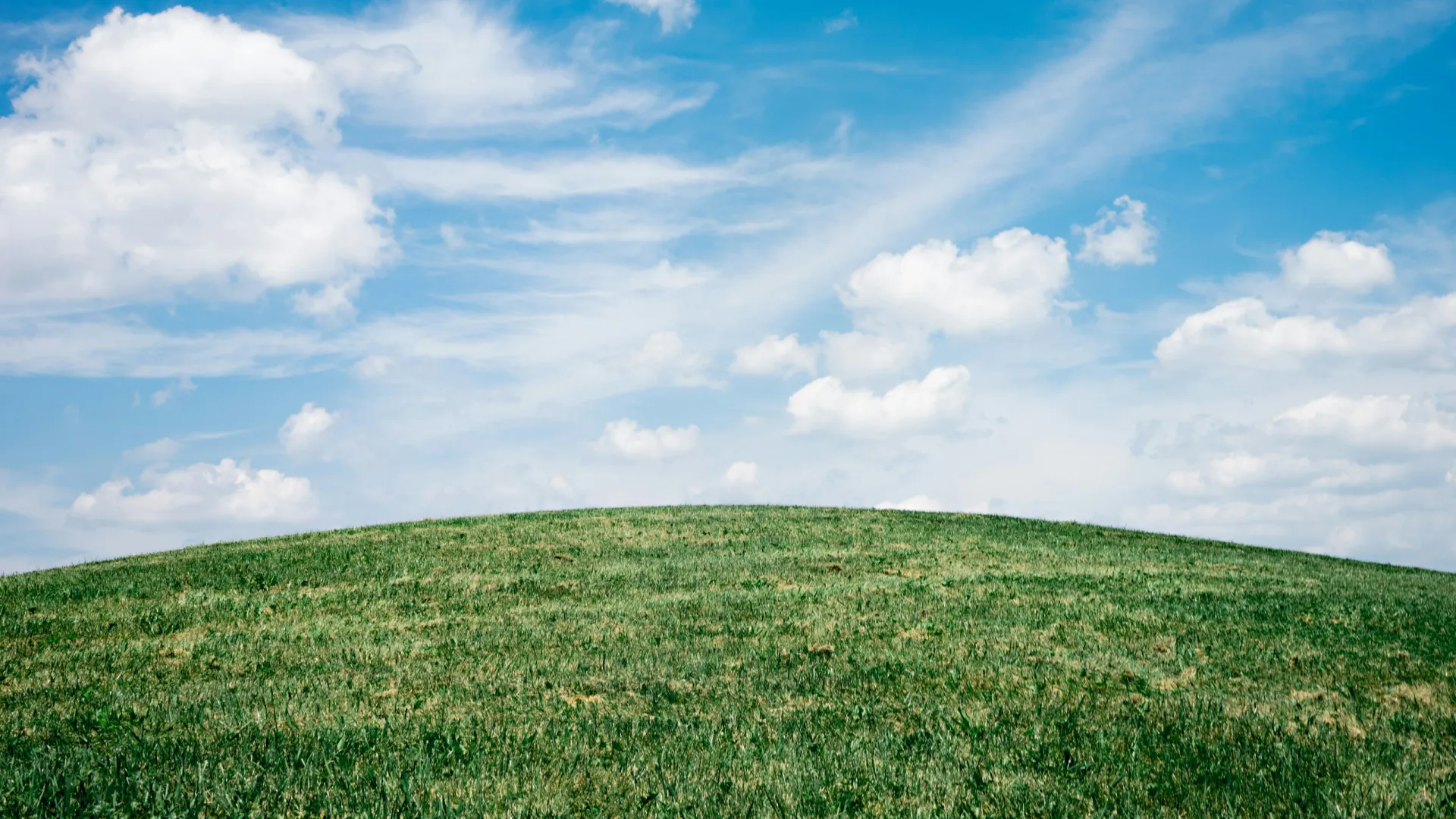 a grassy field with clouds in the sky