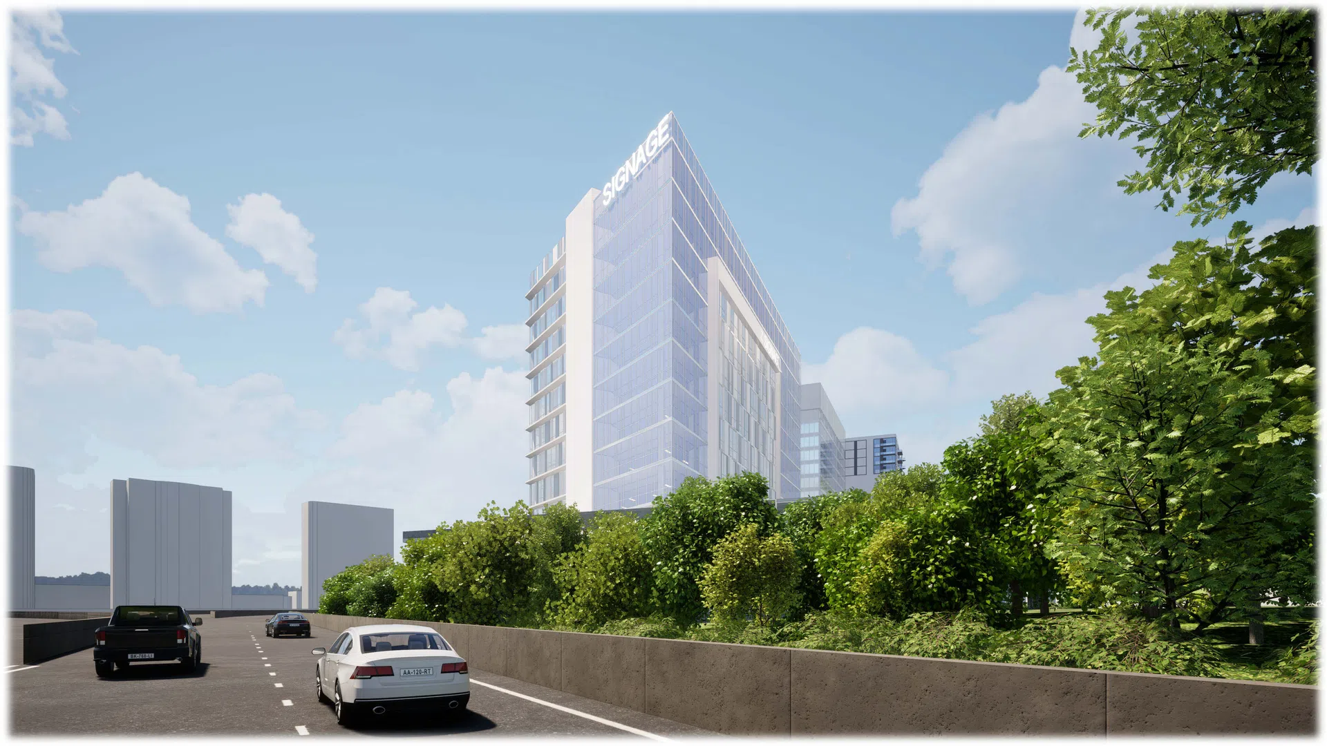 Modern glass office building with signage on top surrounded by trees and cars on the road under blue sky.