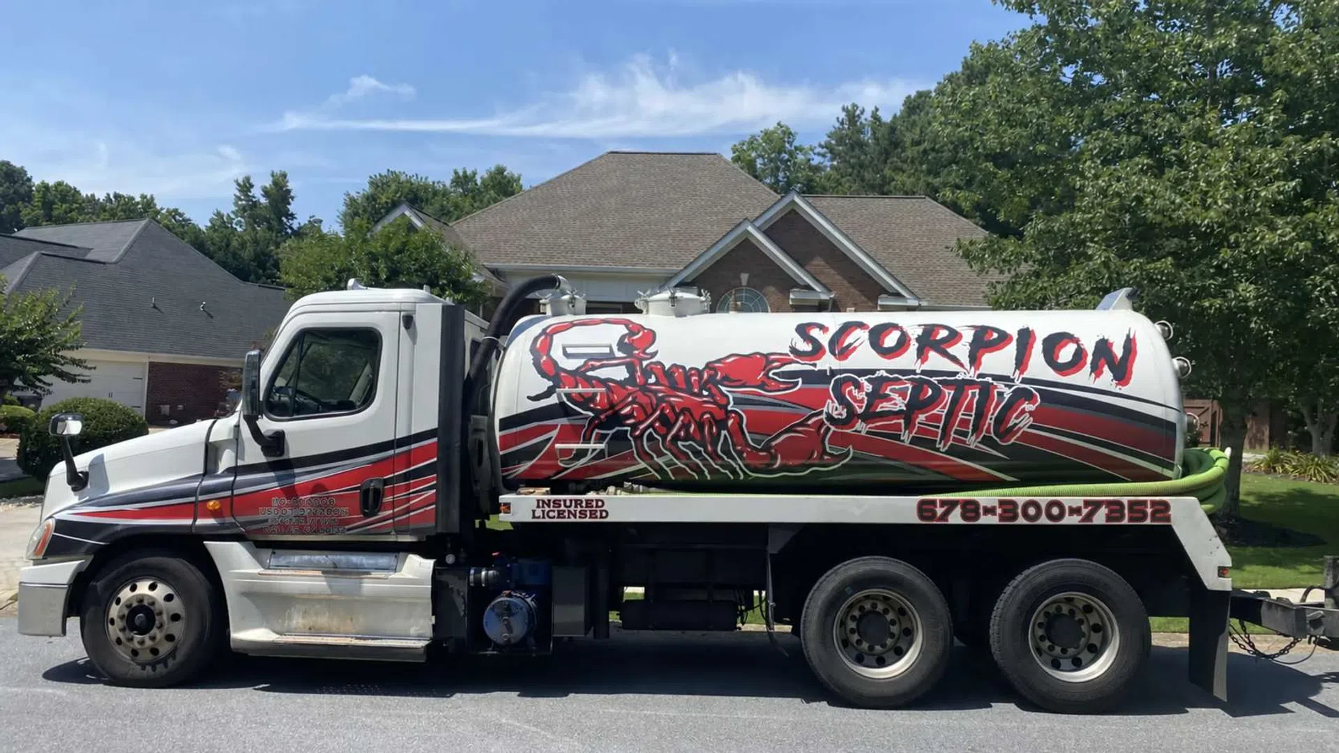 Septic service truck with red scorpion logo and Scorpion Septic text parked on suburban street in front of a house.