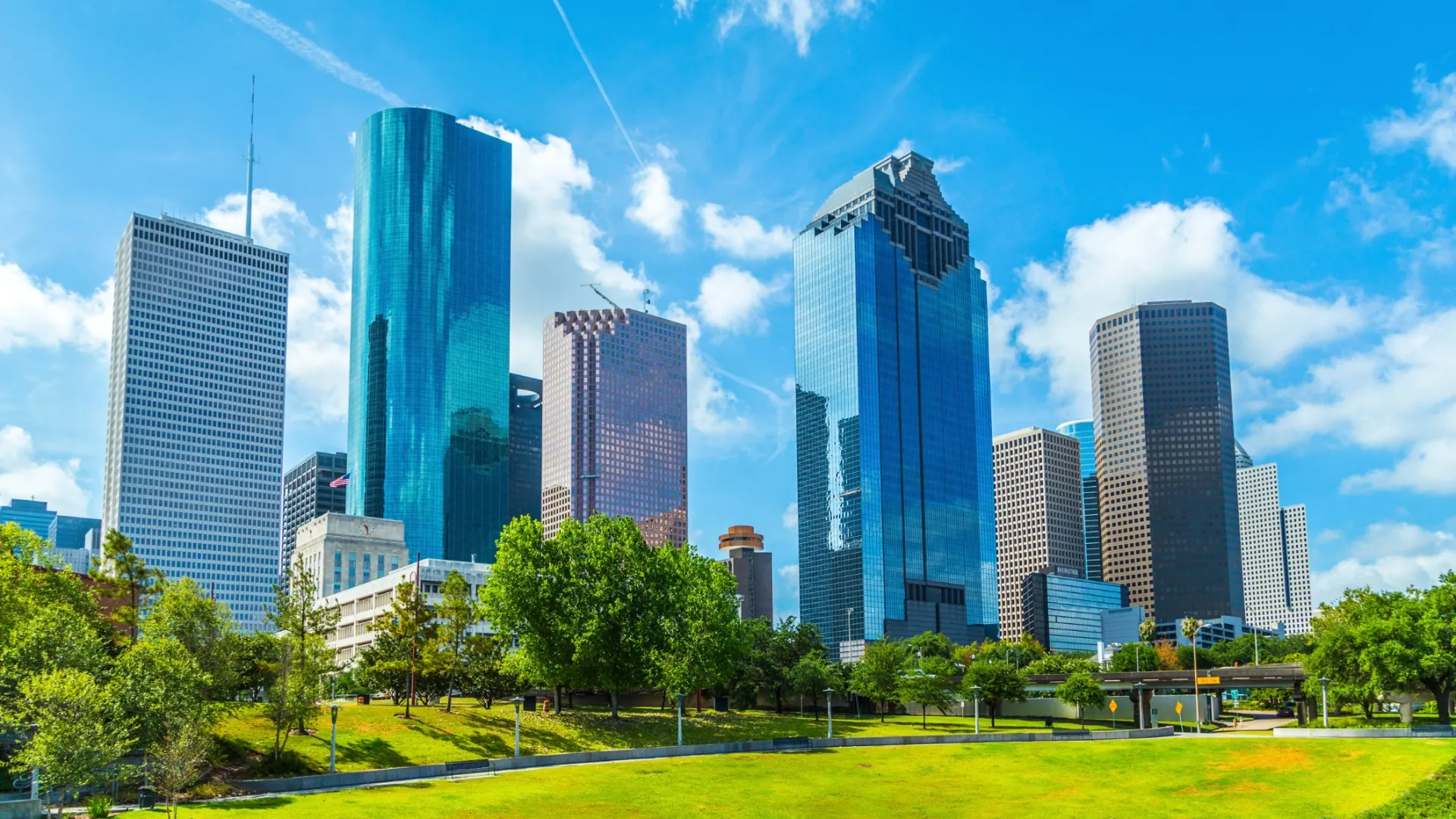 Clear blue sky over Houston city skyline with modern skyscrapers and green park in foreground