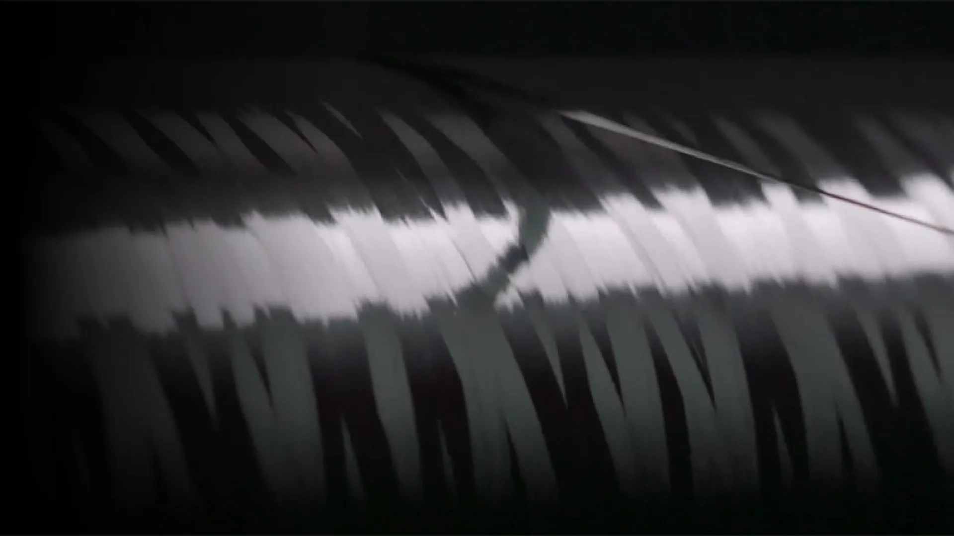 Close-up of a shiny, metallic cylindrical object with reflective light streaks and dark shadows
