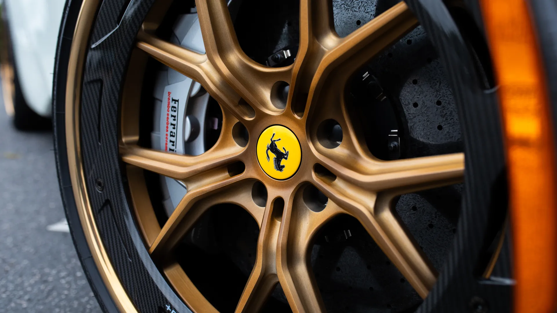 Close-up of a bronze HRE car wheel with carbon fiber rim, yellow brake caliper, and Michelin tire on a dark vehicle.
