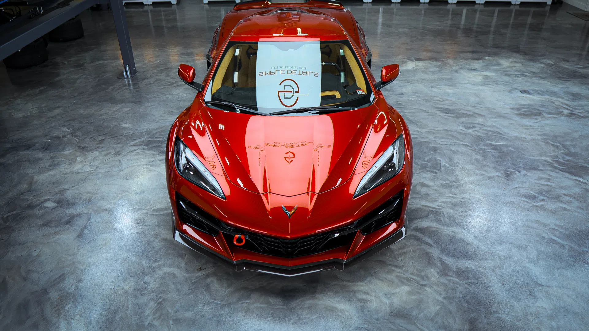 Shiny red sports car with sleek aerodynamic design parked on polished concrete floor indoors