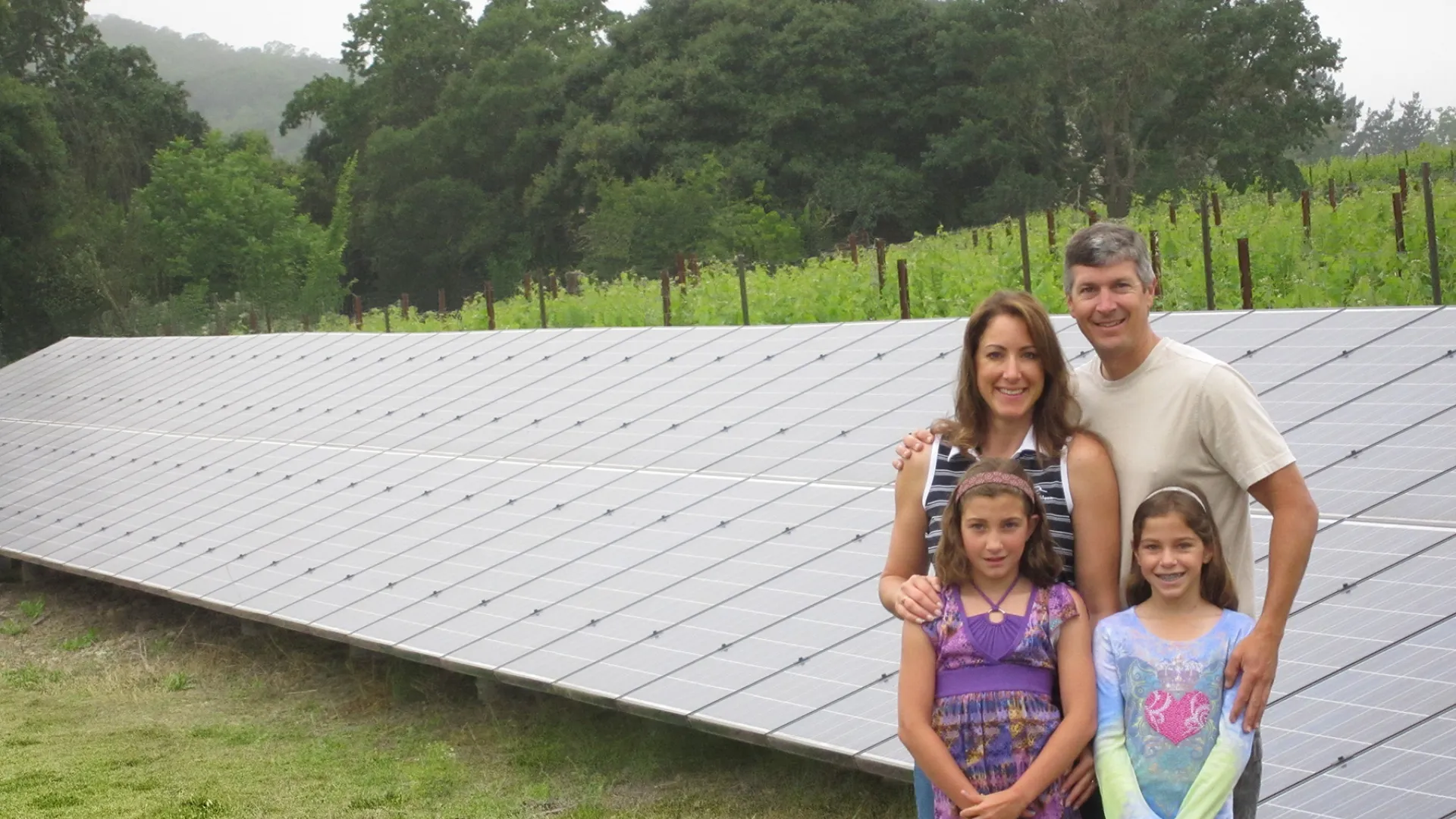 a group of people posing for a photo in front of a solar panel