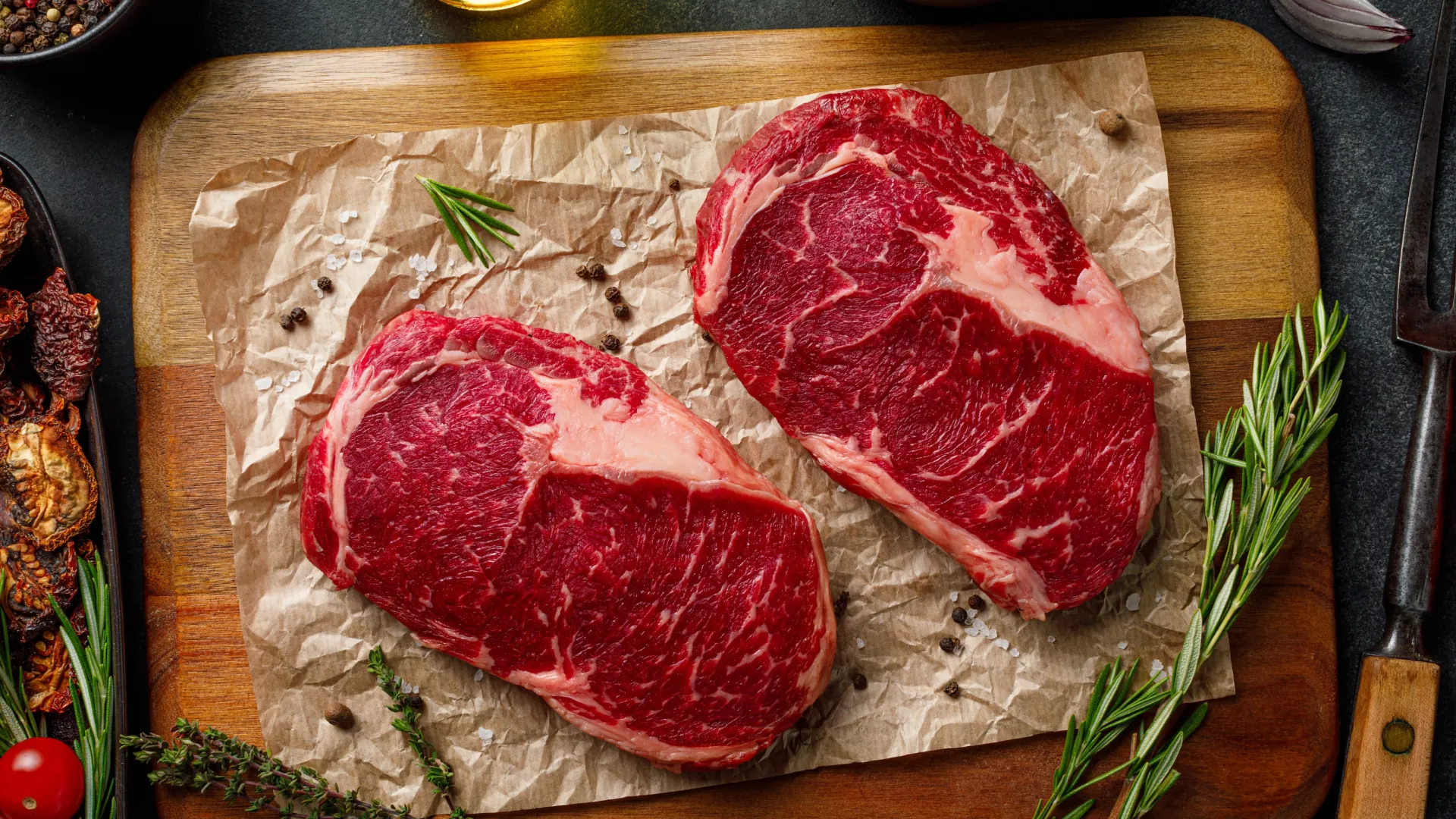 a slab of meat on a cutting board with a knife and a spoon