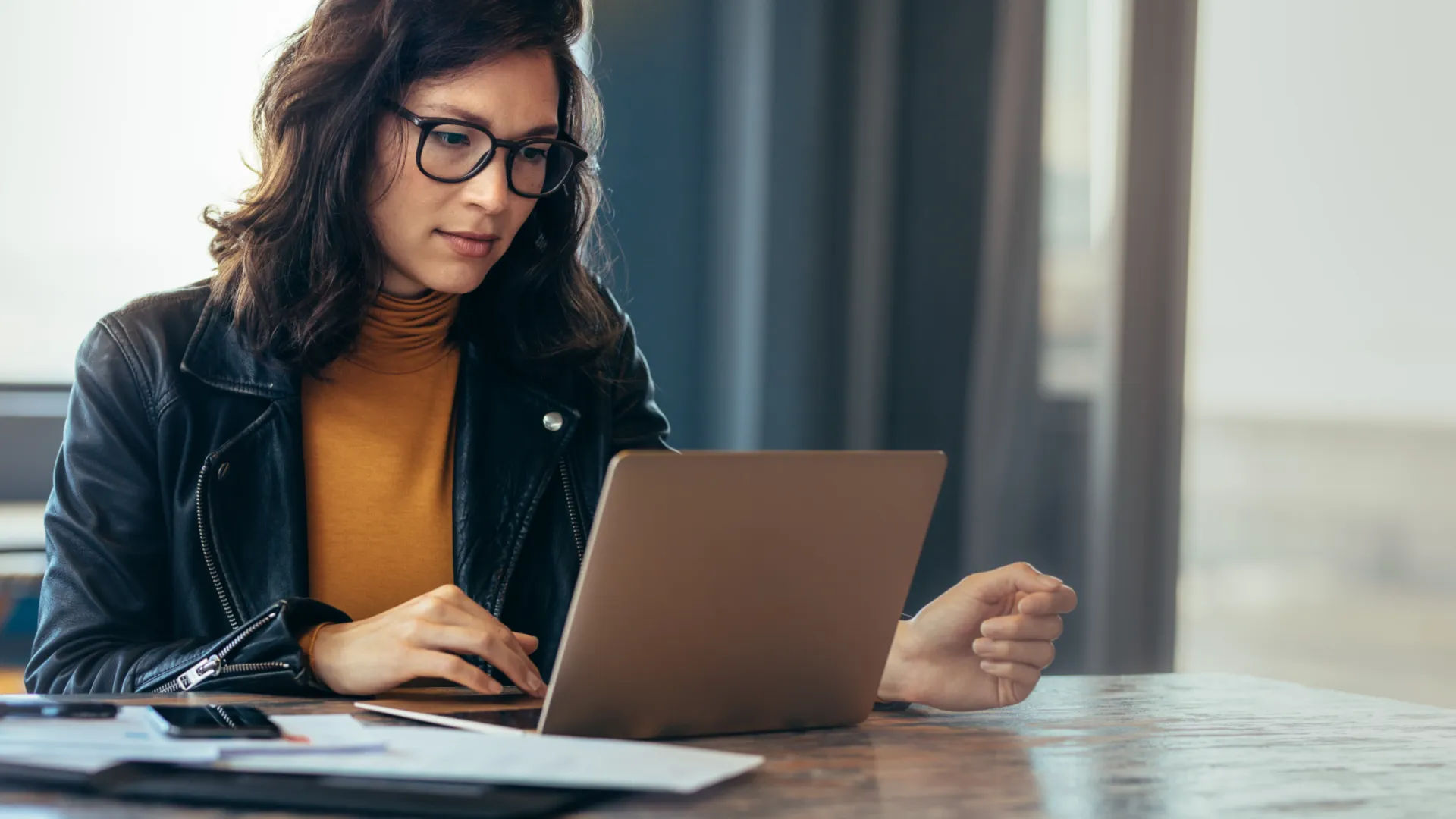 a woman sitting at a table using a laptop computer