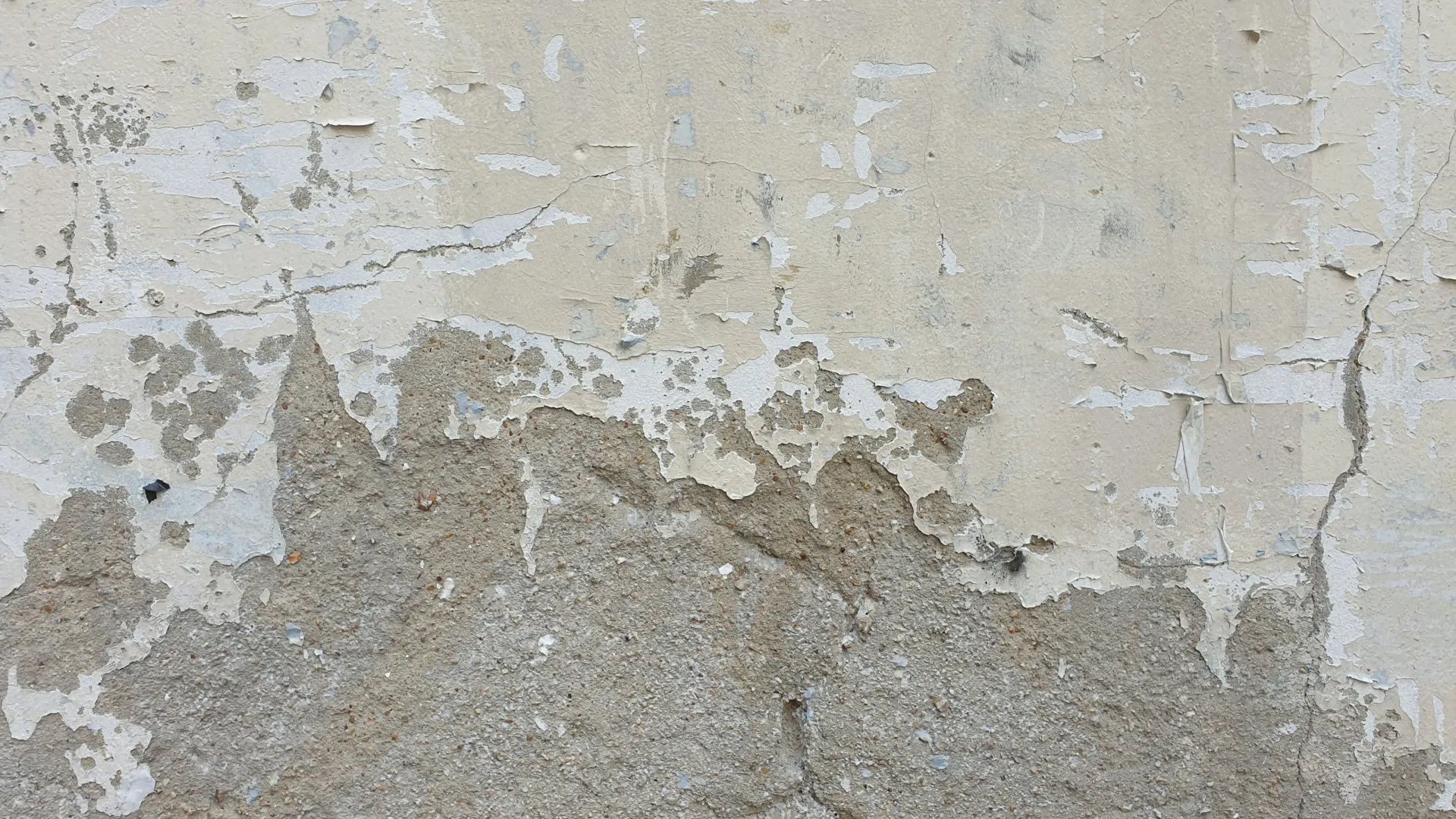 Peeling and cracked glue over a rough concrete wall surface showing weathered texture.
