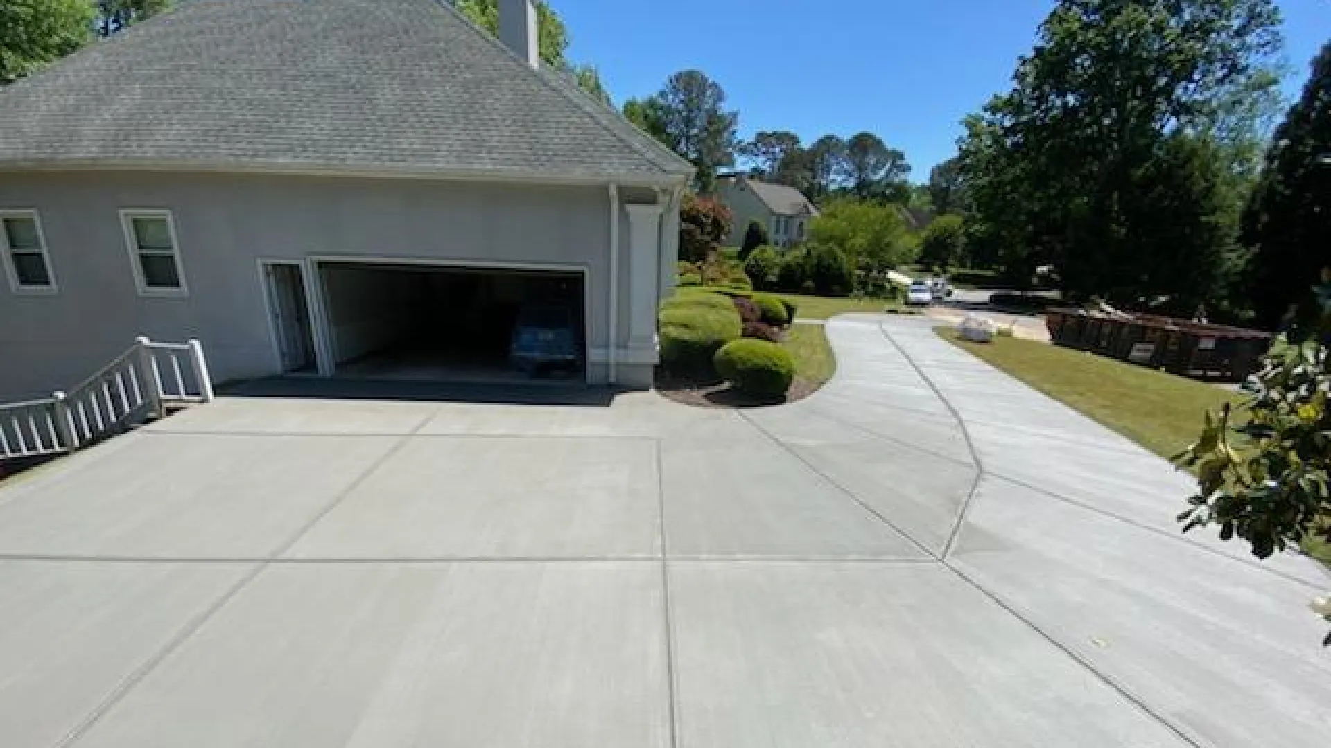 Newly poured clean concrete driveway leading to a residential garage on a sunny day.