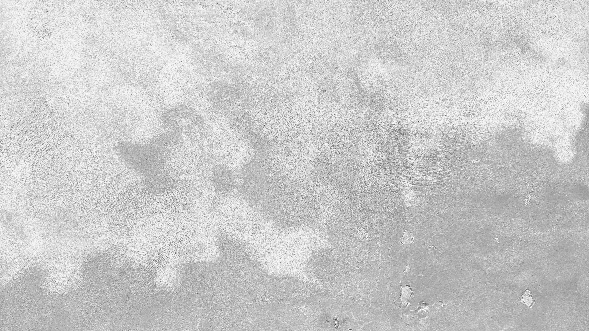 Textured concrete wall surface with light gray and white patches and rough uneven patterns.