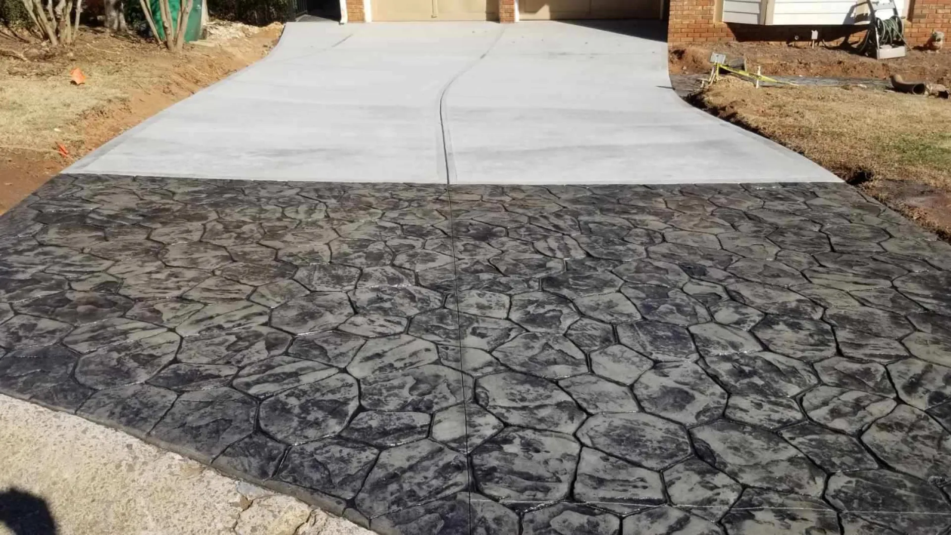 Stunning stamped concrete driveway featuring a stone pattern and fresh gray finish.