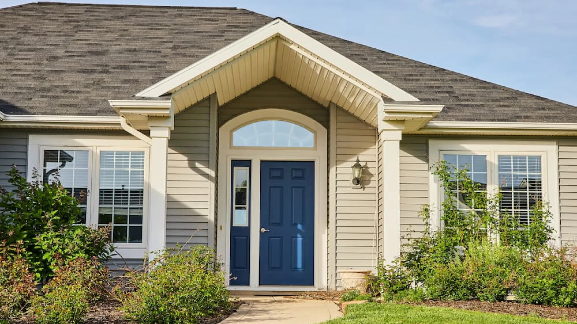 Beautiful new front door installation on a blue-grey siding house, promoting exterior door replacement and improved curb appeal.