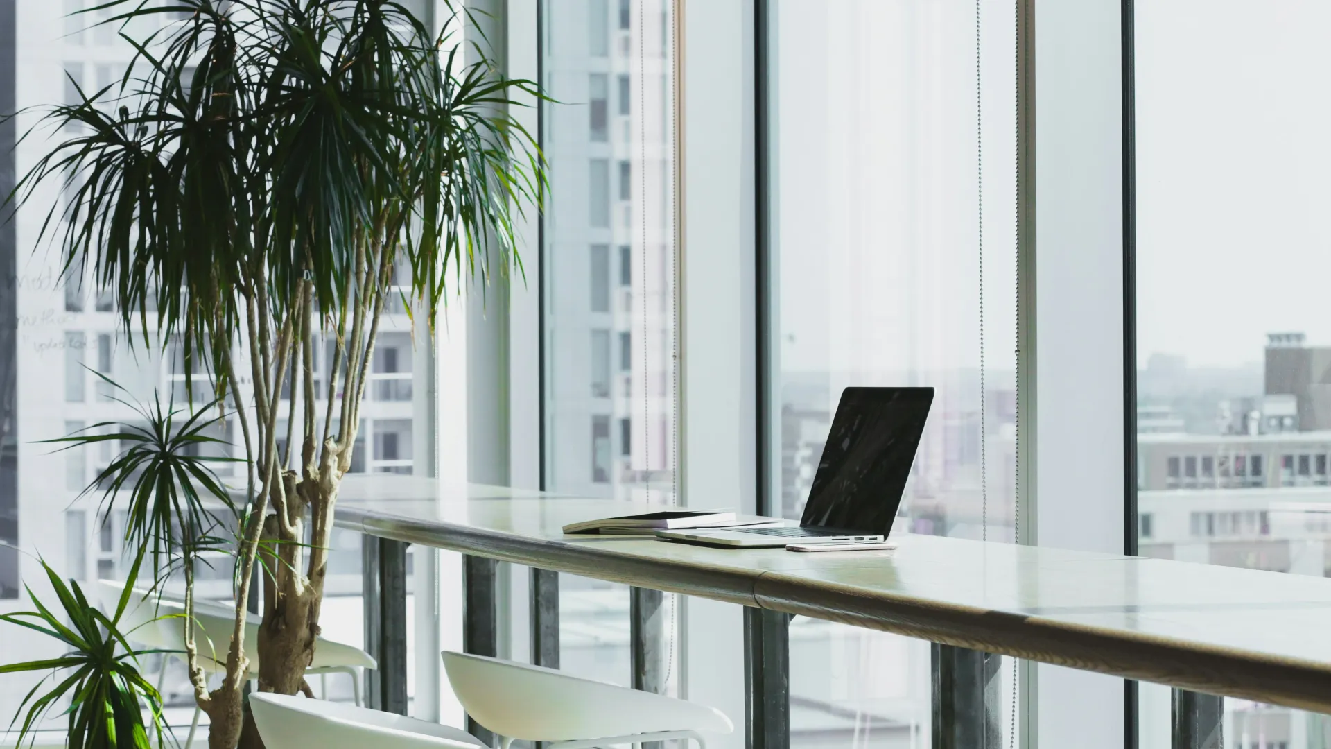 a table with a laptop and chairs by a window