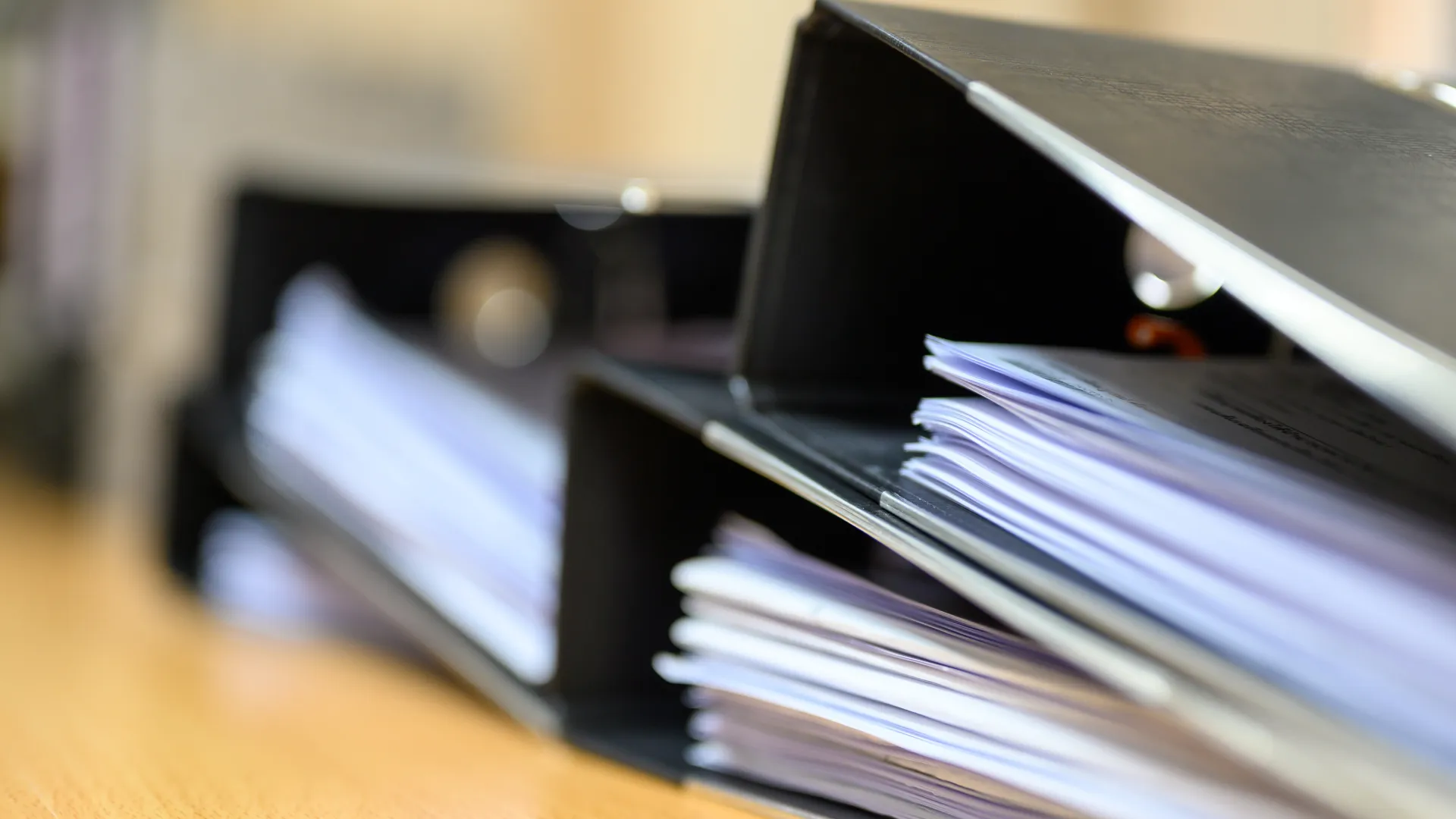 a stack of black binders with paper inside