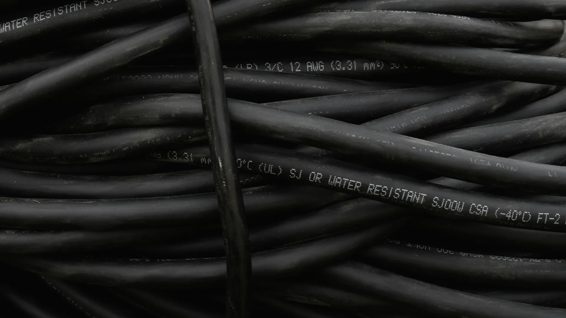 Close-up of coiled black water-resistant electrical cables with printed technical specifications.