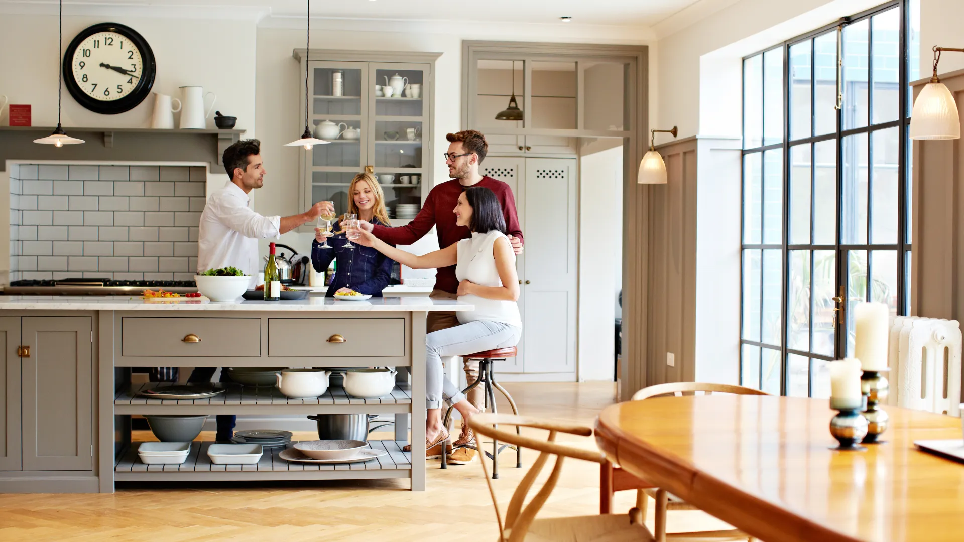 Friends gathered around a wooden table sharing drinks and snacks in a cozy social setting.