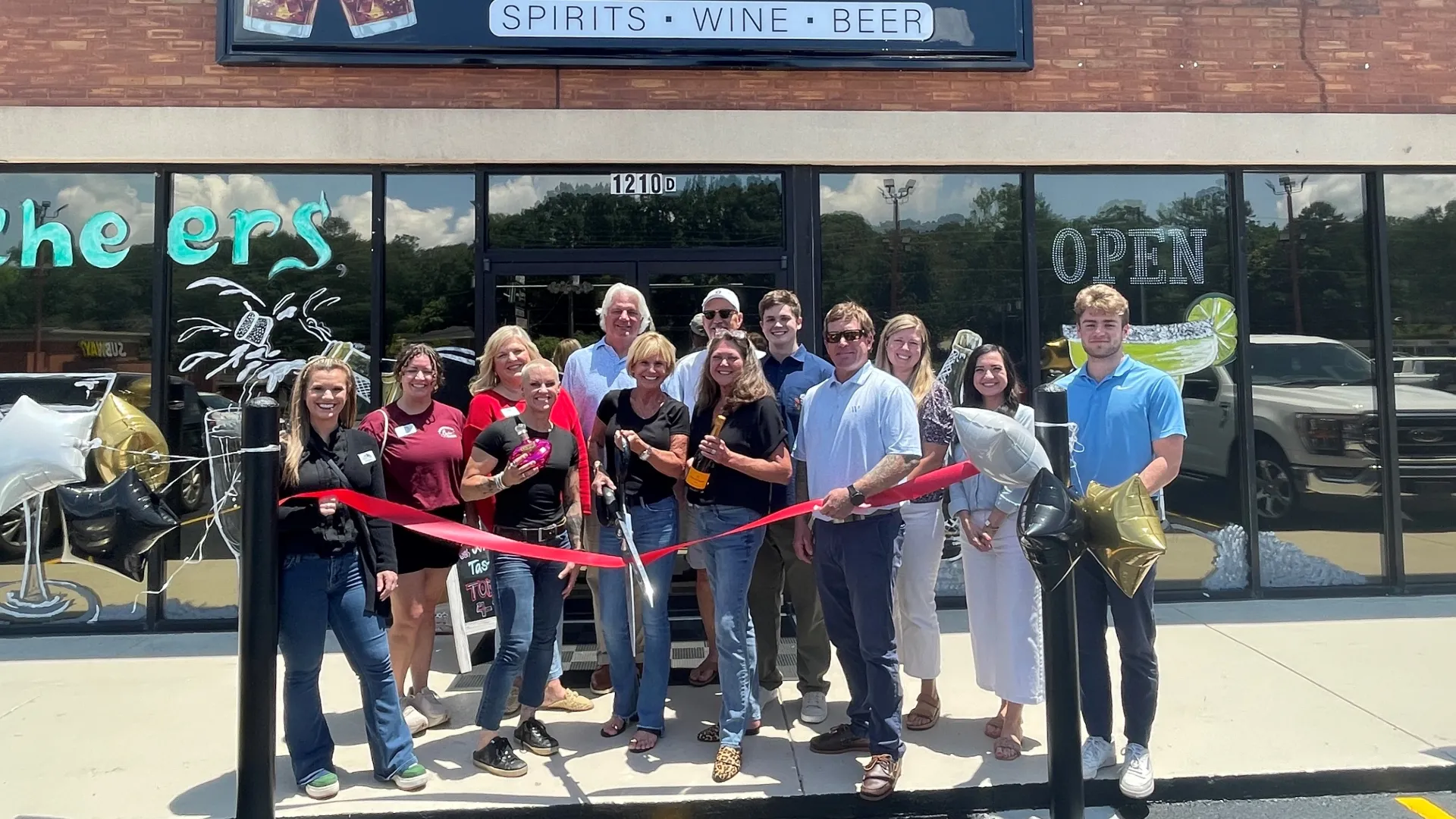 Group of people celebrating the grand opening of The Big Chill spirits, wine, and beer store with a ribbon-cutting event.