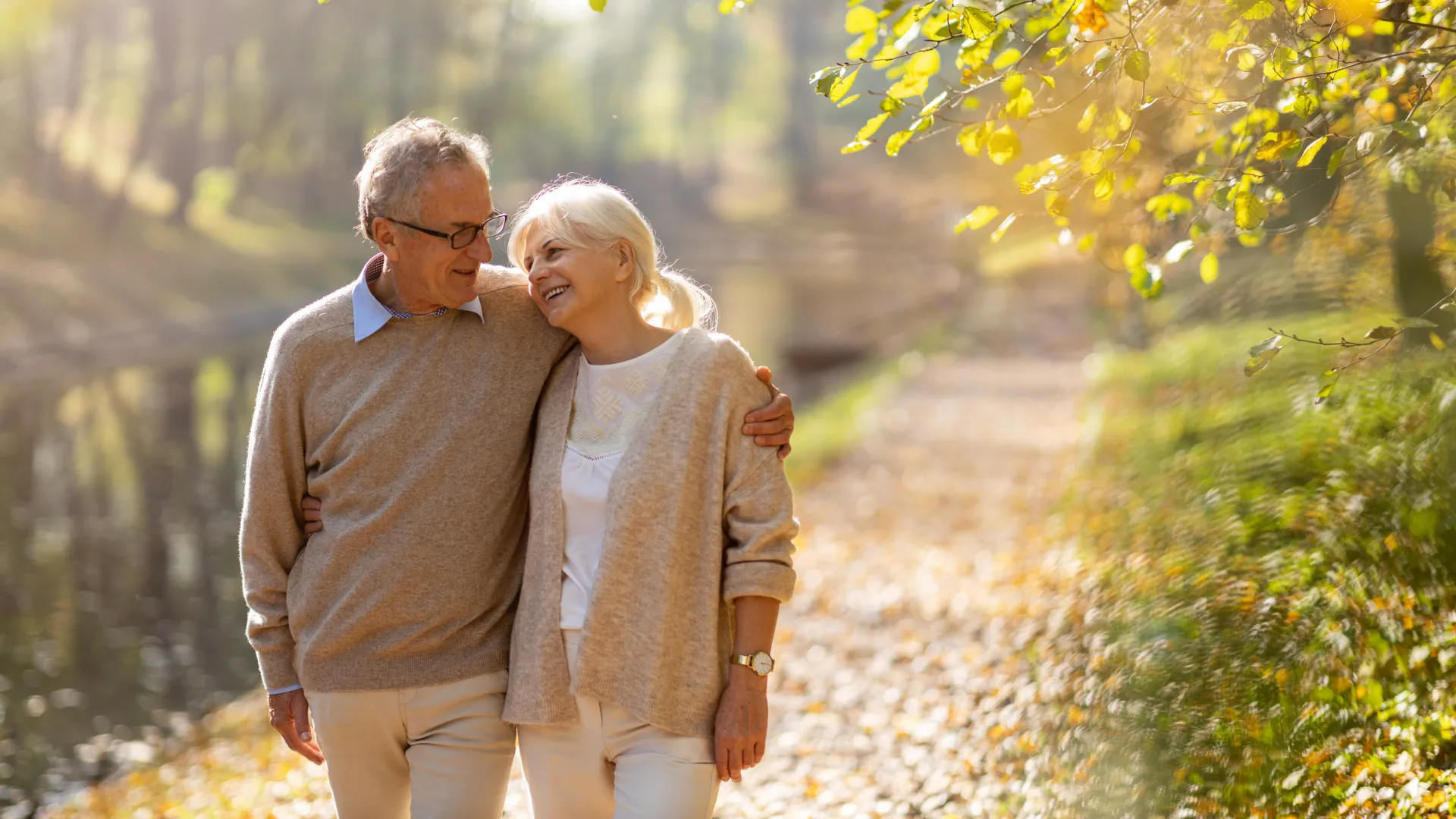 a man and woman walking on a path with trees and bushes