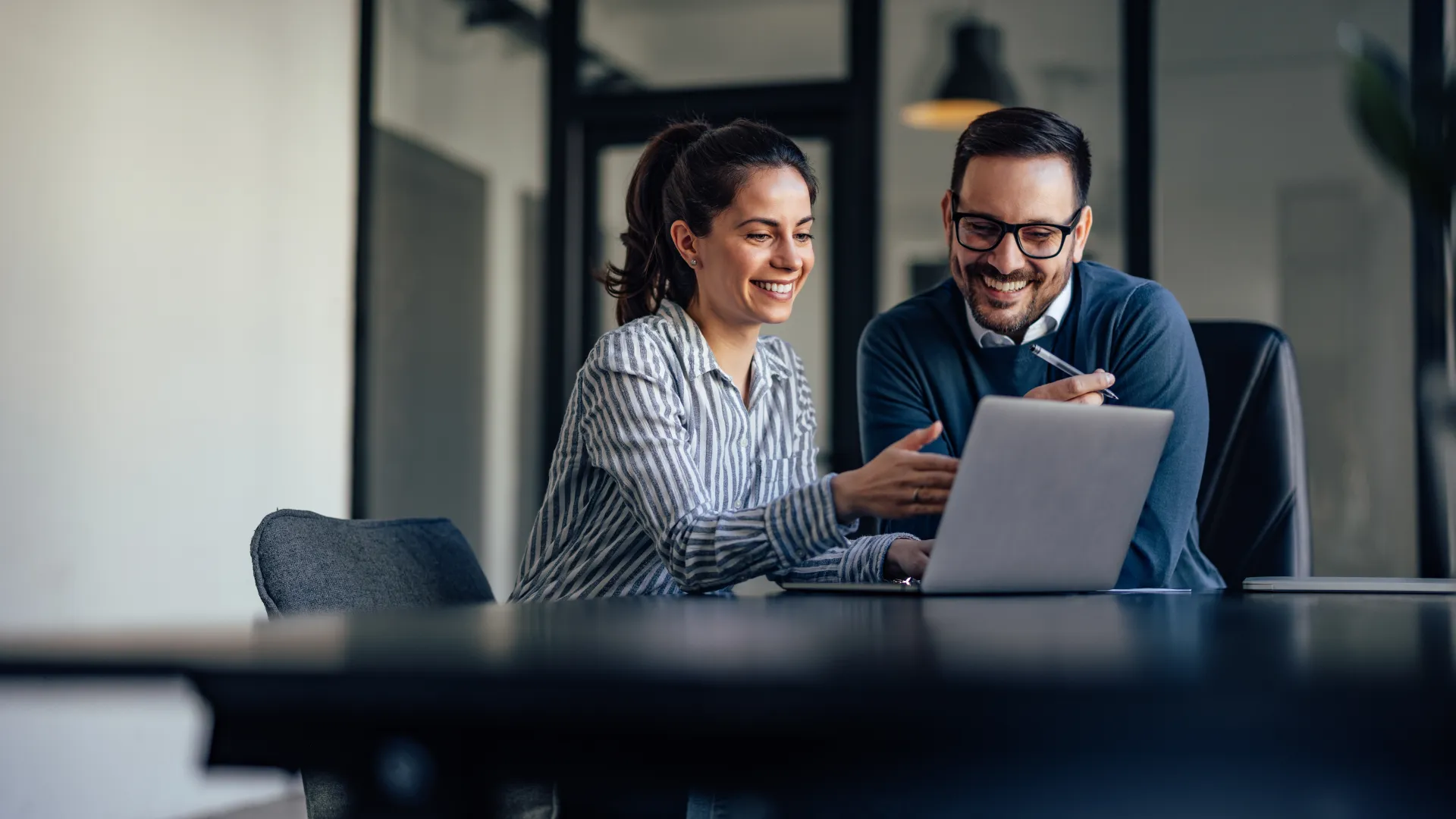 a man and a woman looking at a laptop