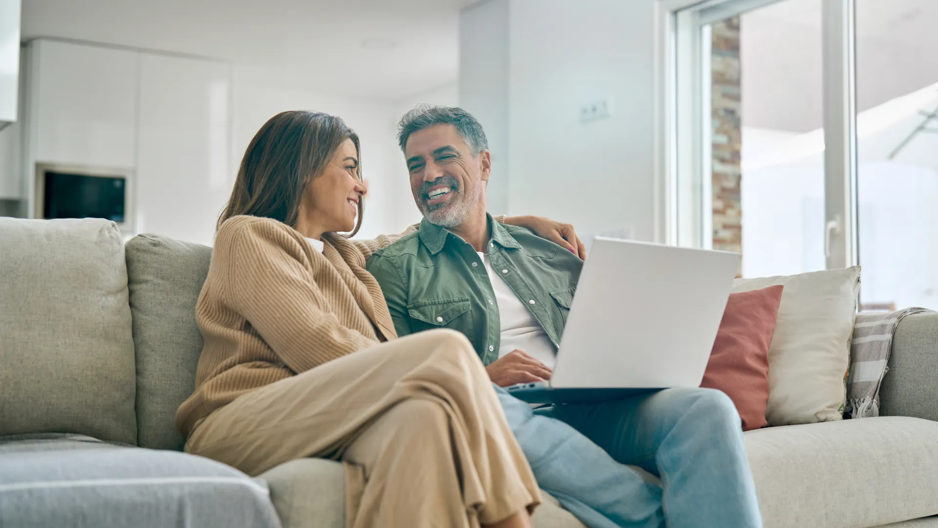a man and woman sitting on a couch with a laptop