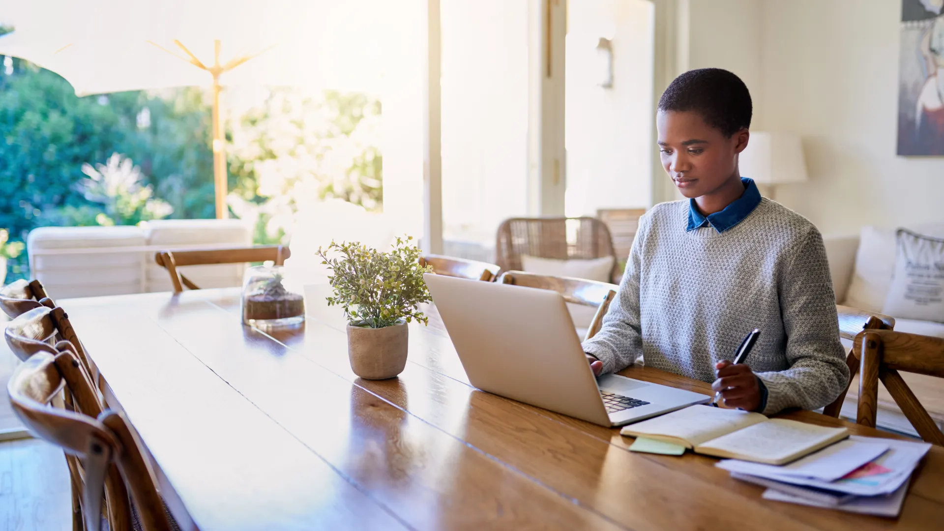 a woman sitting at a table with a laptop and pen