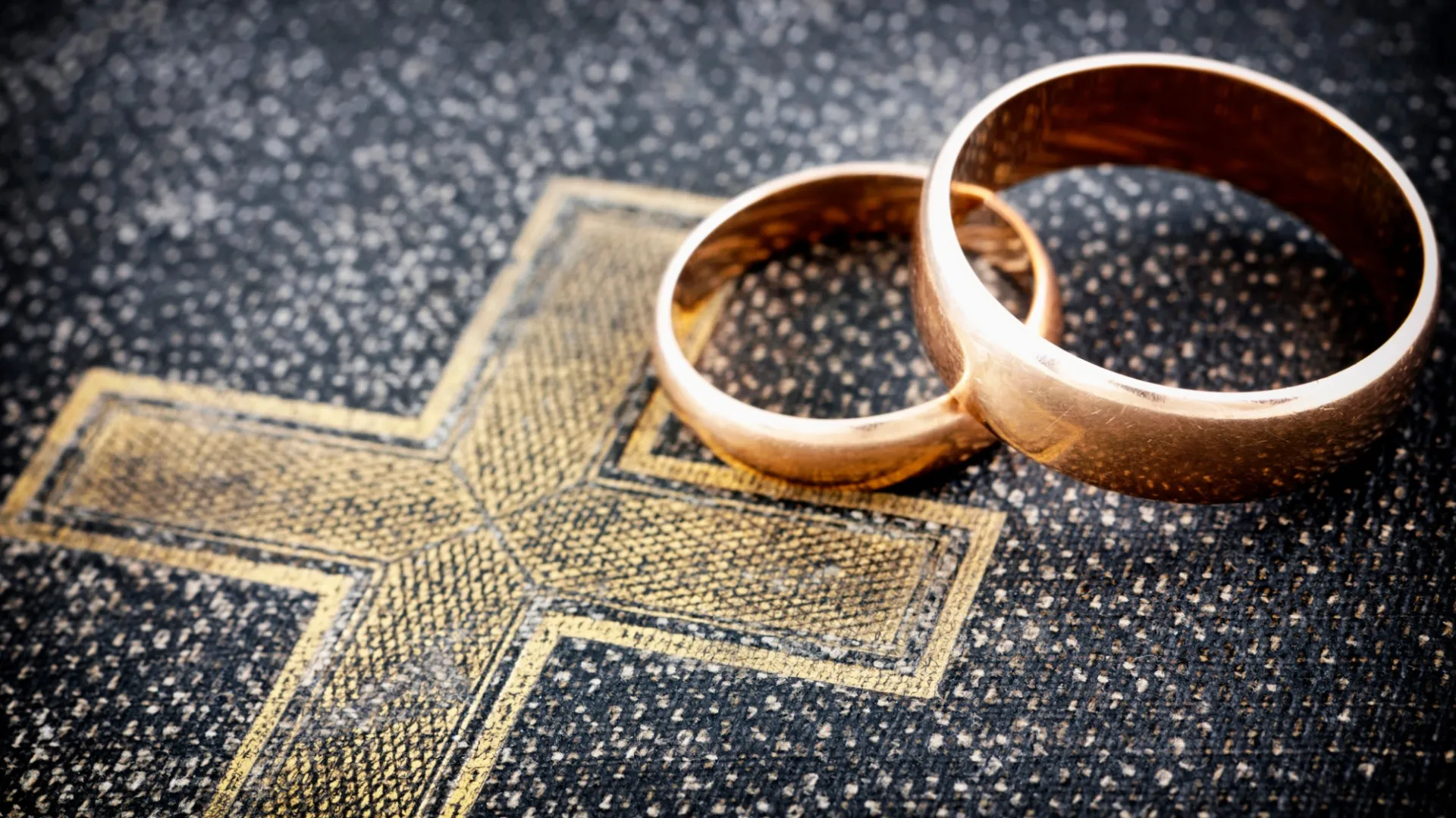 a pair of gold rings on a pile of money