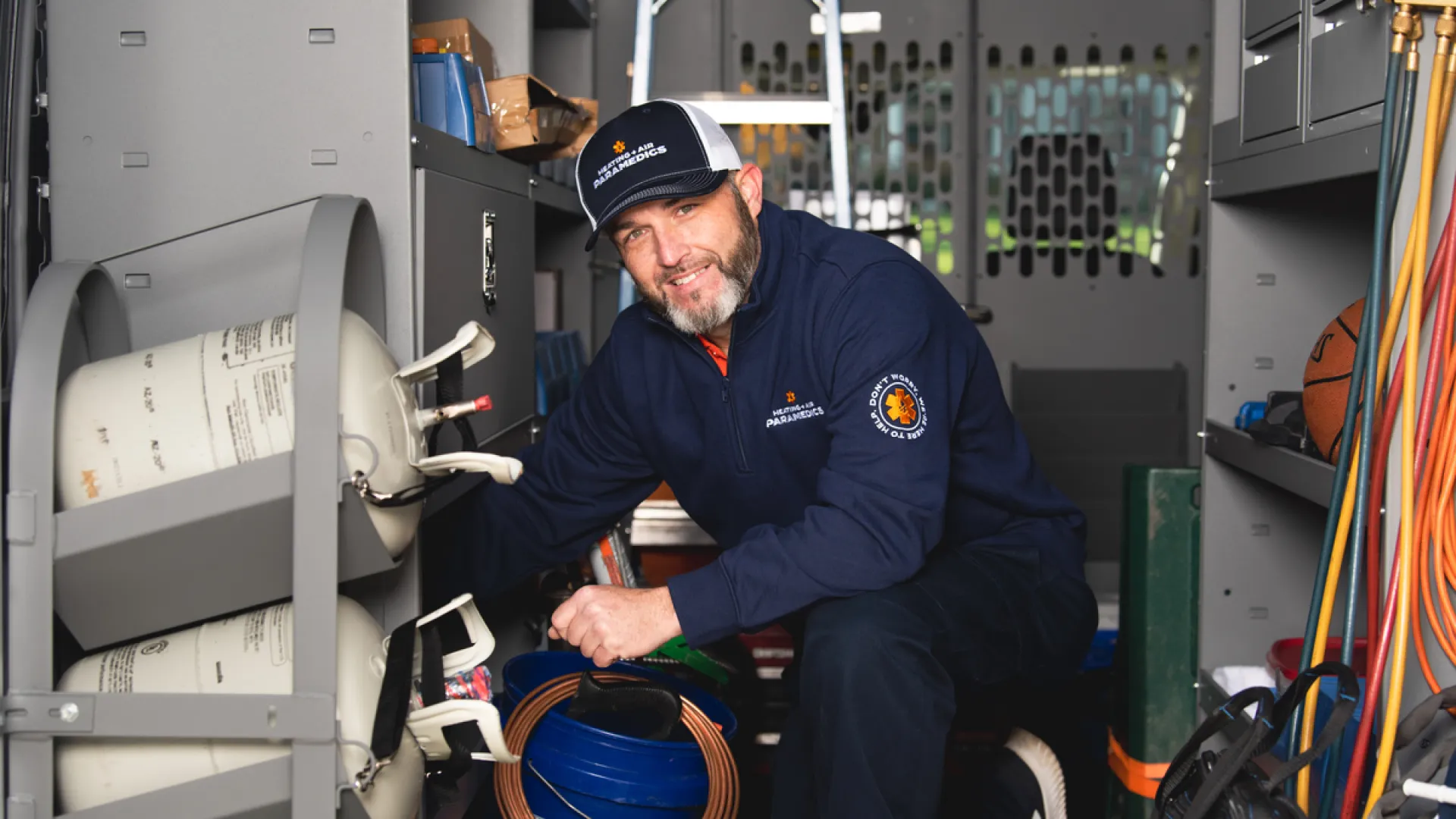 Technician working inside service van surrounded by tools, hoses, and gas cylinders.
