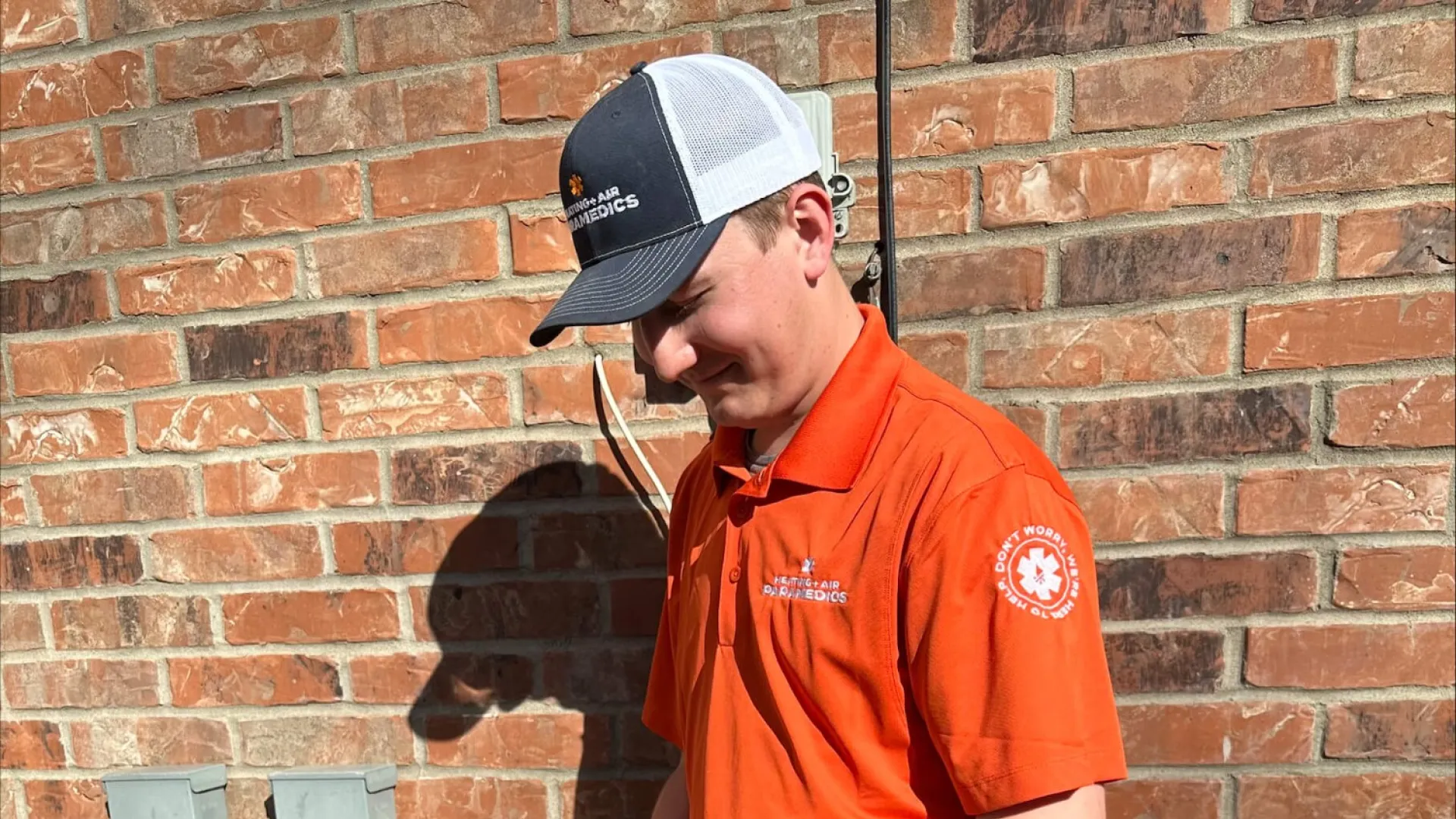 a man wearing an orange shirt and blue pants holding a black and white object