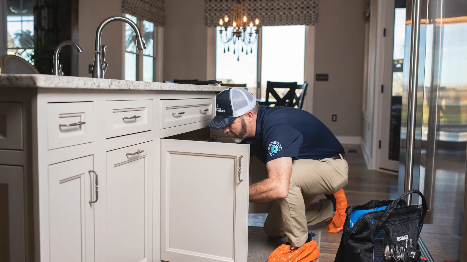 A plumber performing a sink repair in a kitchen.