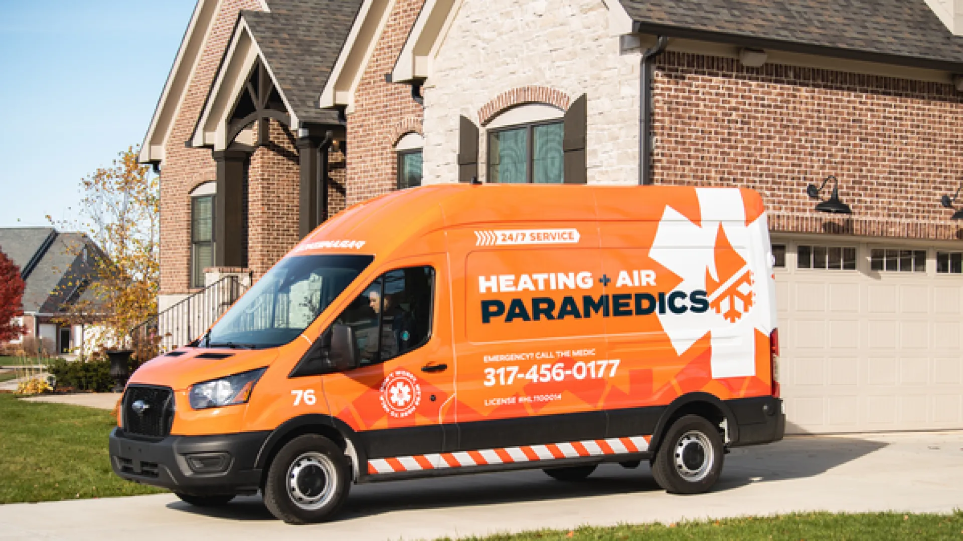 Bright orange service van for Heating & Air Paramedics parked in front of a residential home.