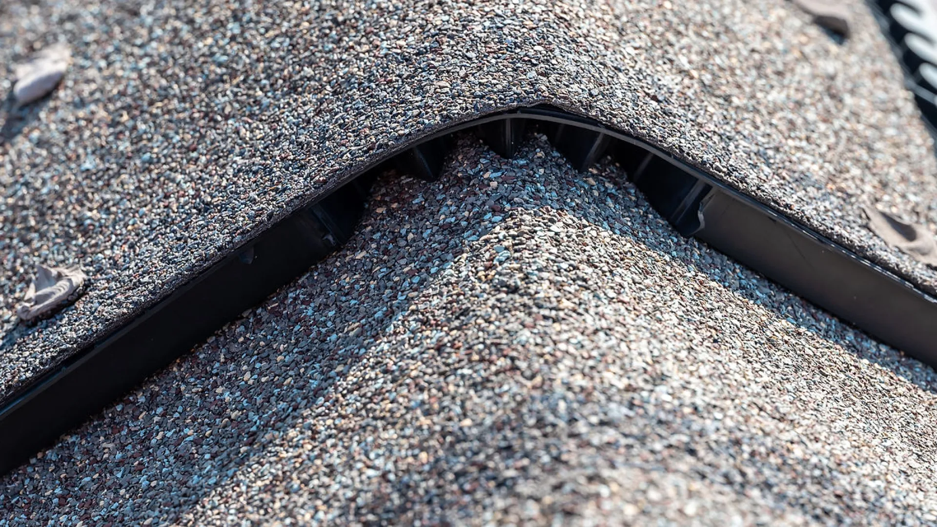 Close-up of a roof ridge vent installed on asphalt shingle roofing for attic ventilation.