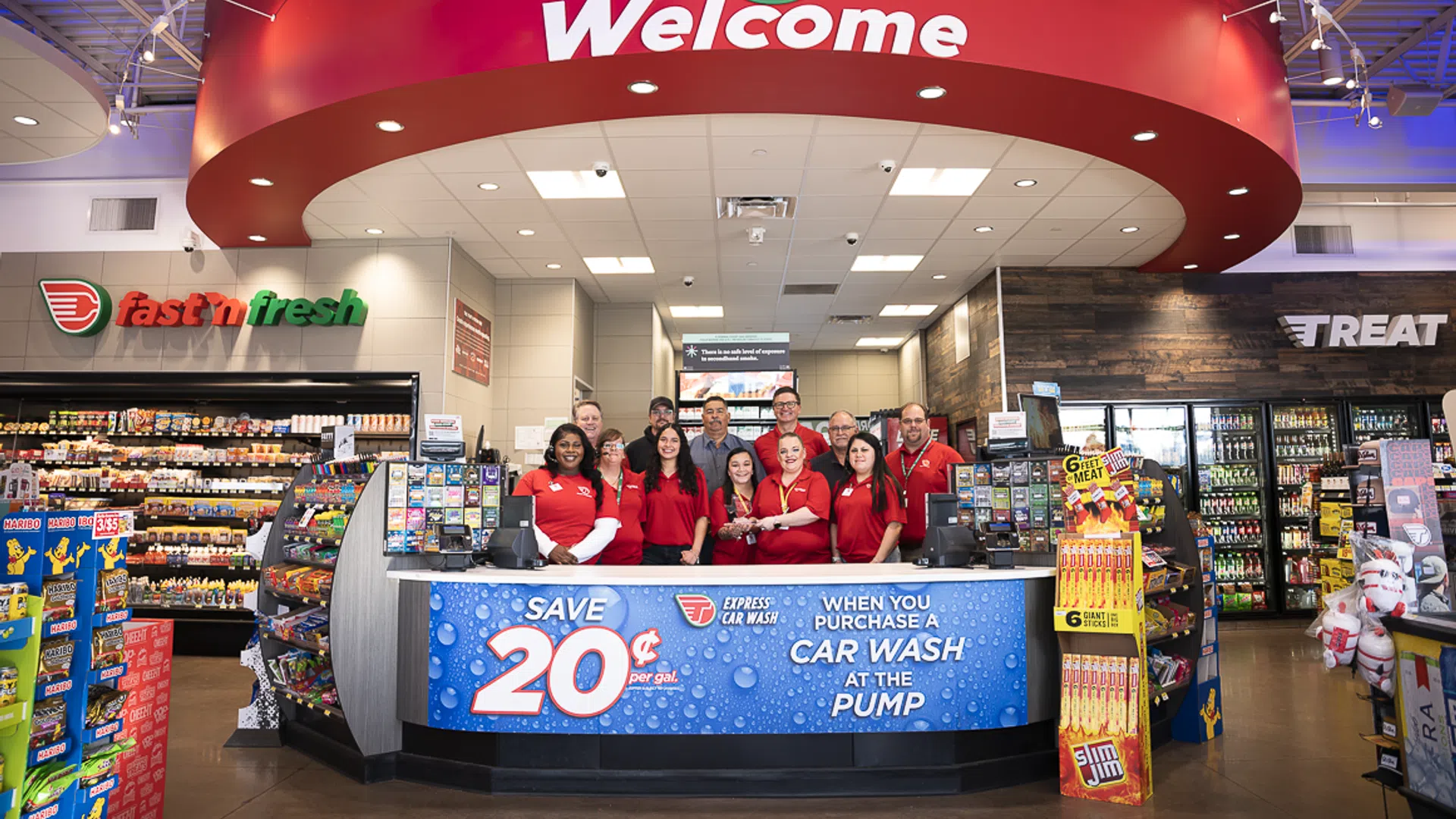Welcoming team at a convenience store with vibrant signage and car wash promotion.