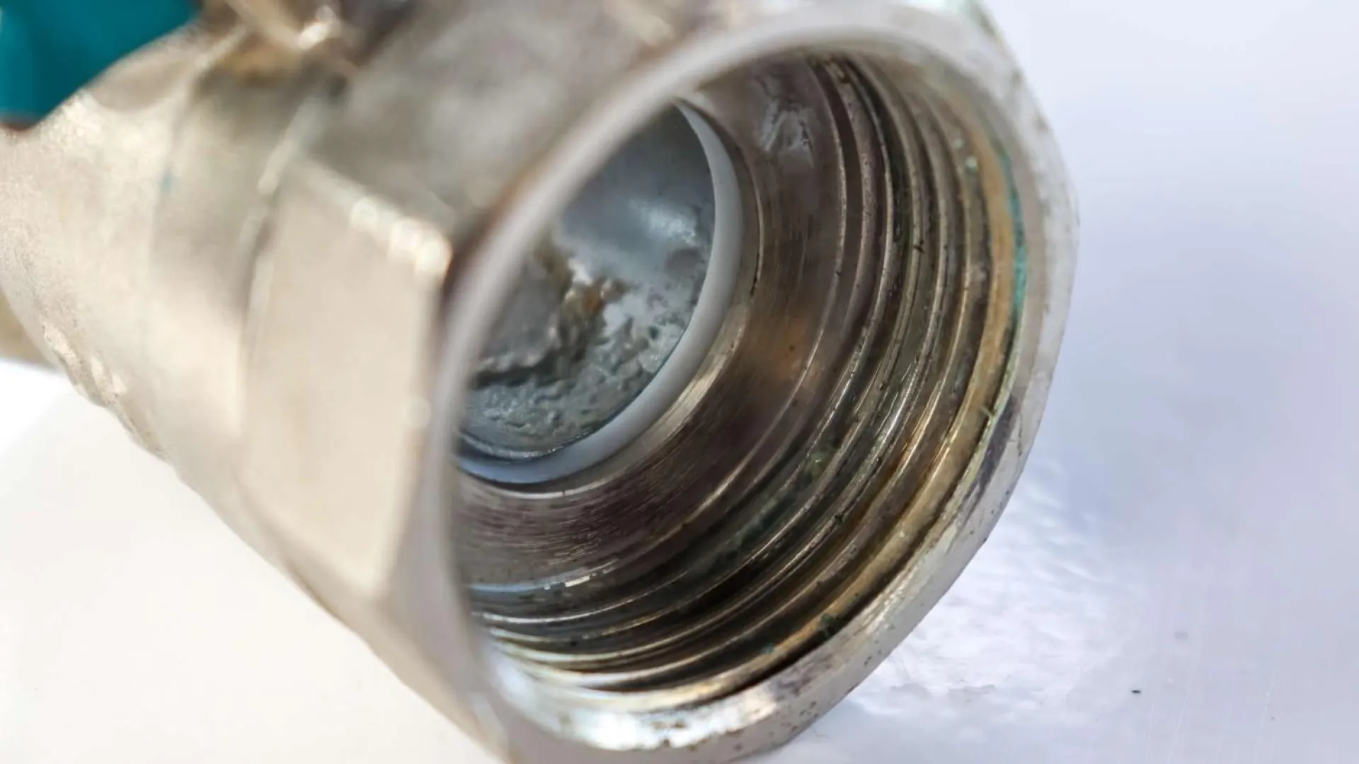 Close-up of a corroded metal pipe thread with visible rust and wear against a white background