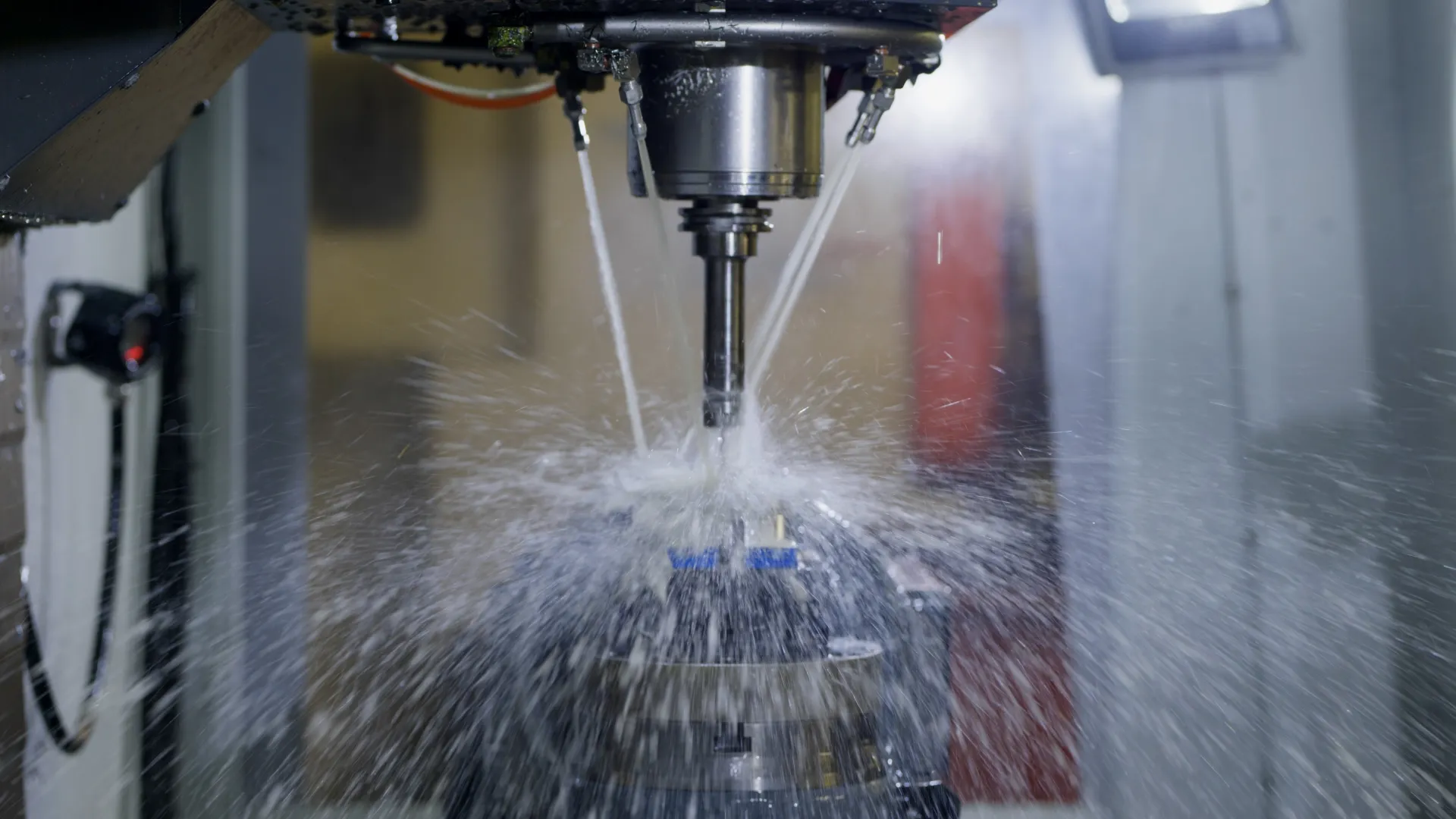 CNC machine cutting metal with coolant spray in an industrial workshop environment.