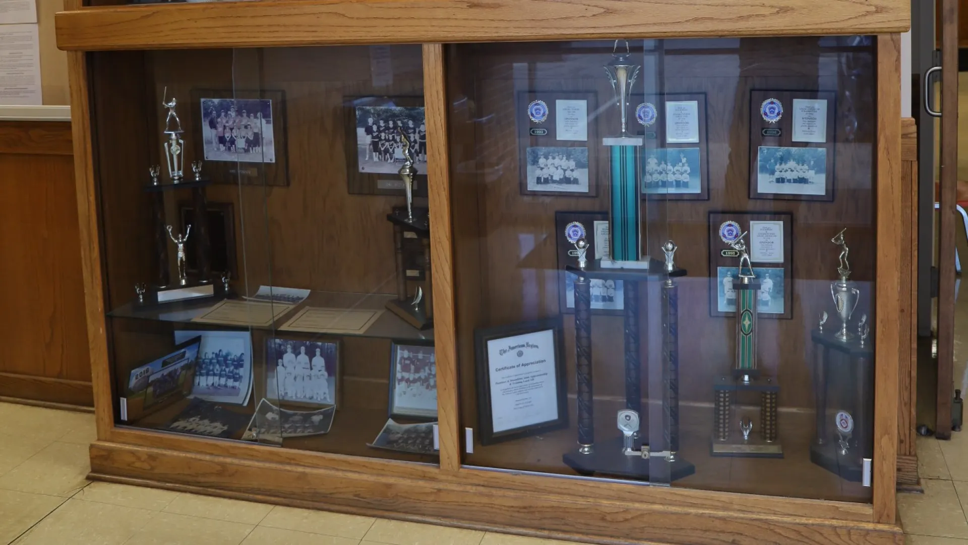Display case featuring awards, trophies, and plaques in a well-lit office environment.